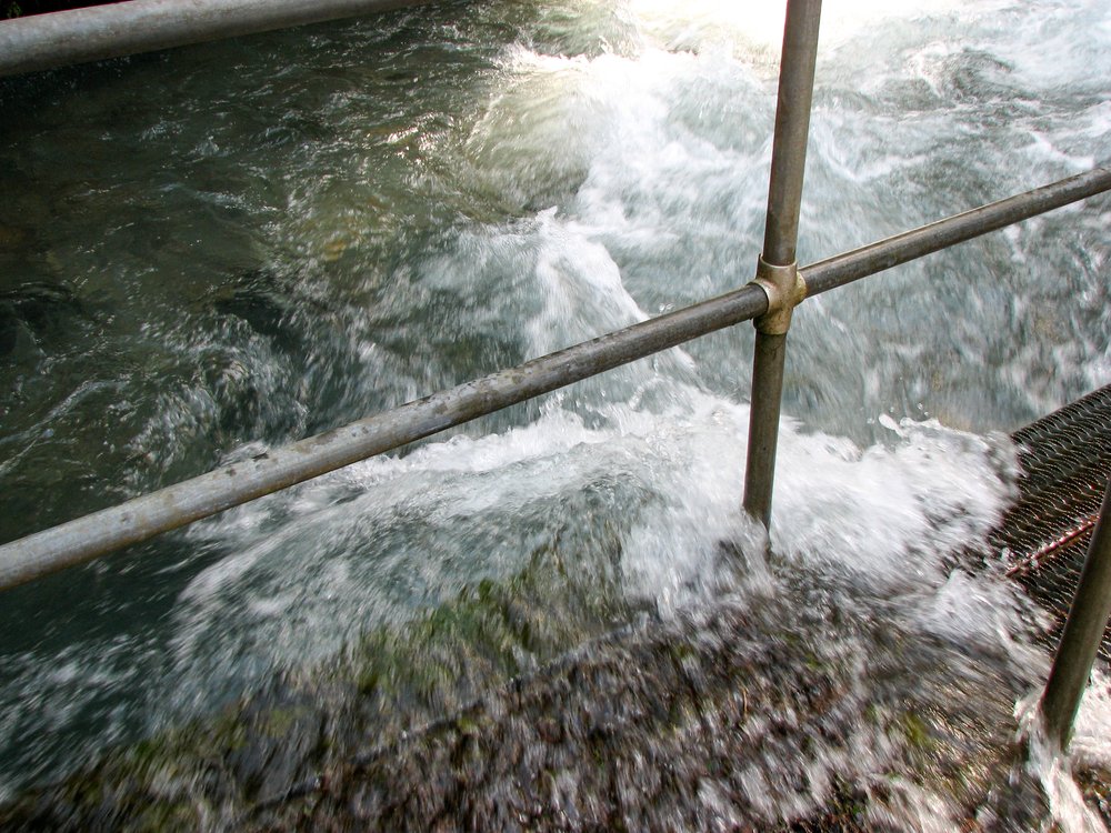 water spilling over walkway of lower dam