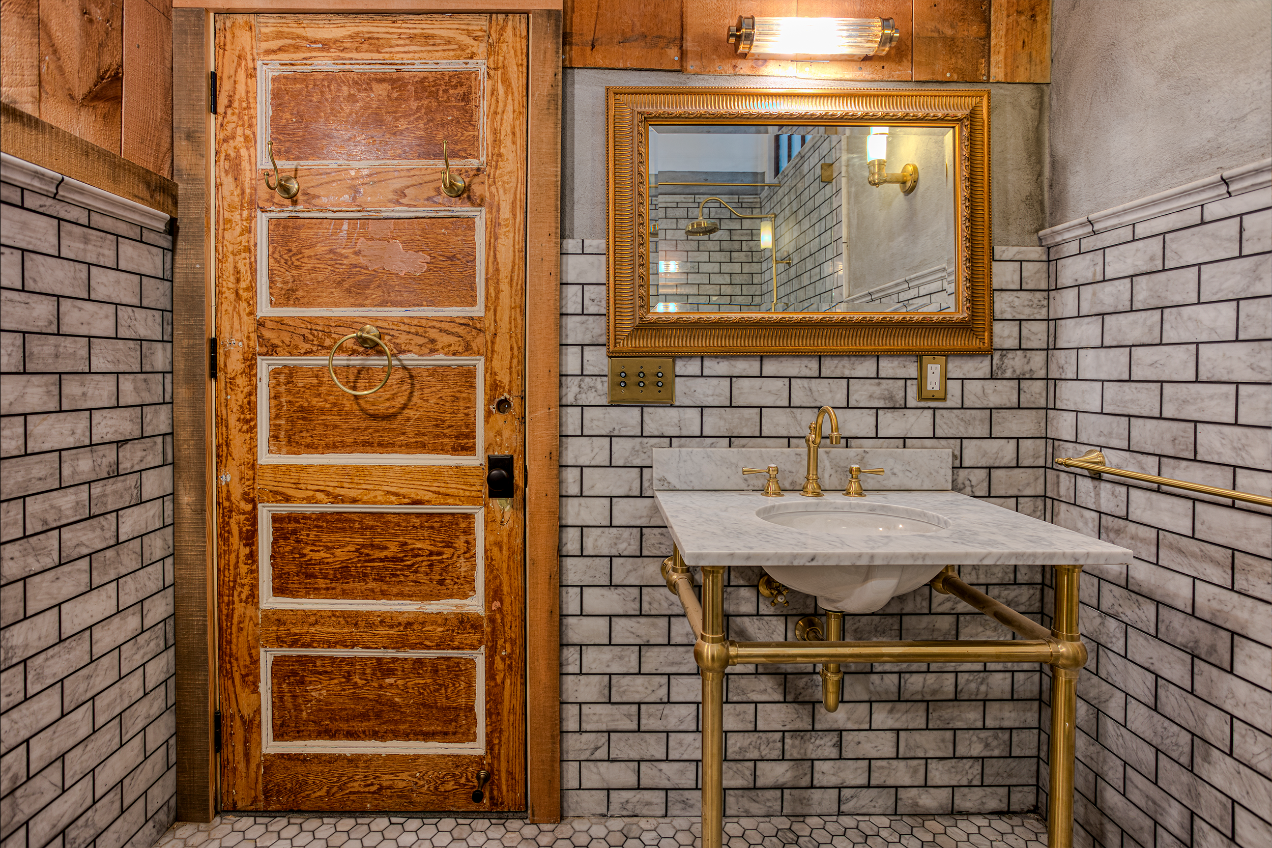 Reclaimed 120 year old oak door from Bed Sty demo. Marble deco Console sink on antique brass stand. Carrera tile. Troweled cement walls.