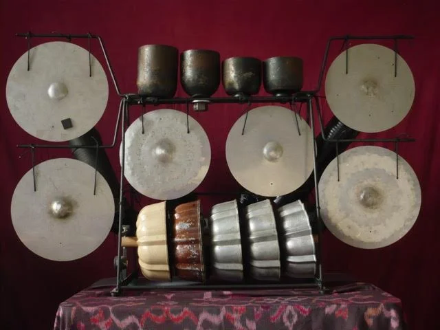 The instrument evolves. It may be split into three instruments, an octave plus of chromatic bells, additional bundt pans, and two racks which can each hold four gongs. These could then be played by a trio.