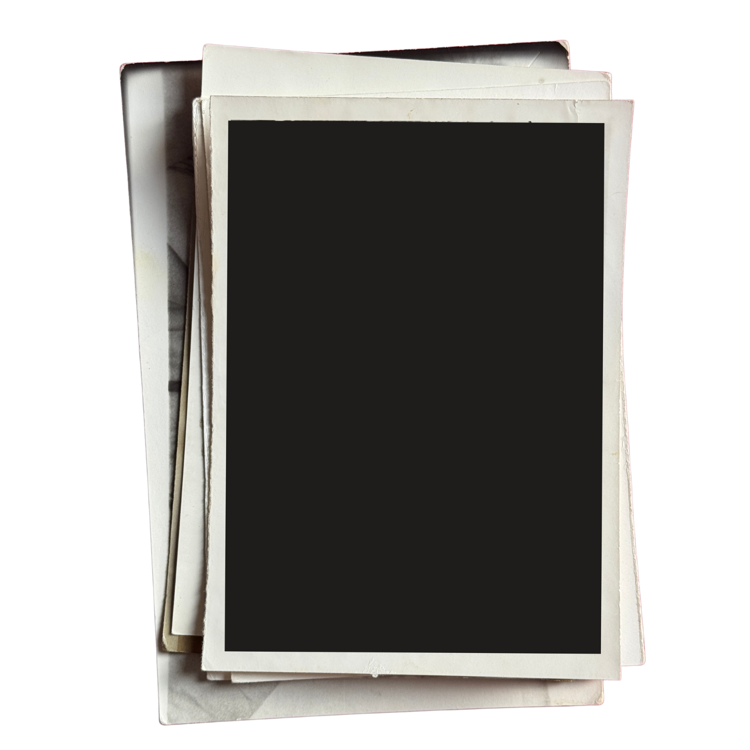 Stack of blank or black-bordered photographs or postcards on top of white envelopes or paper.