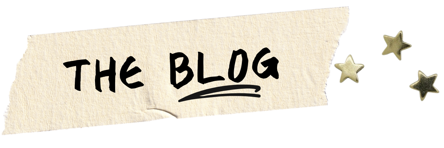 A torn piece of beige textured paper with handwritten black text that says 'THE BLOG' and three metallic star-shaped decorations next to it.