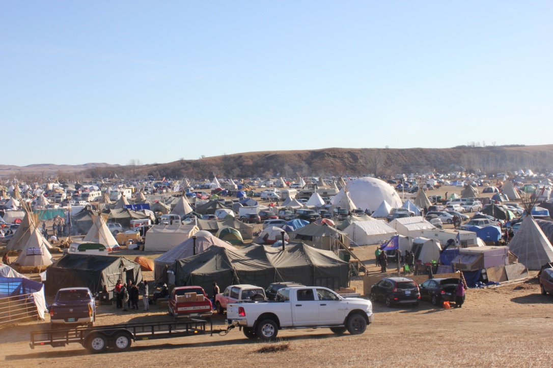   Teepees, canvas tents, RVs, yurts, corrals, moving vans, and adapted buses pepper the camp known as Oceti Sakowin. The white geodesic dome is a donation from Burning Man, and serves as a communal space for meals, orientation meetings, action meetin