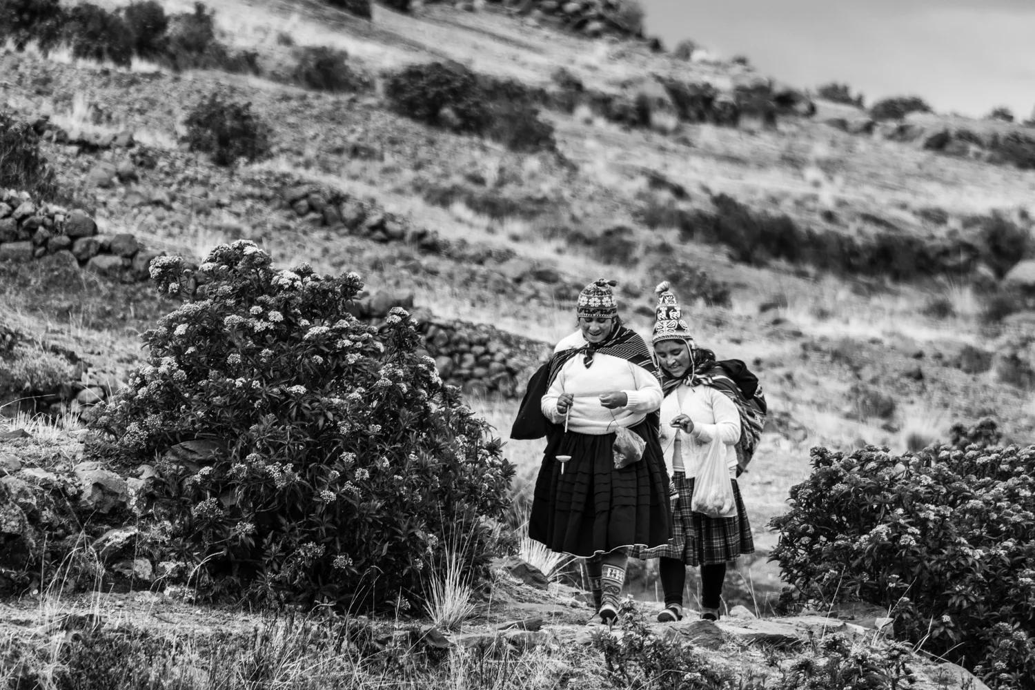 A couple of women are climbing the hills of Amantani island to reach the ruins of Pachatata . There, they will hopefully sell handicrafts to the tourists who visit the island.