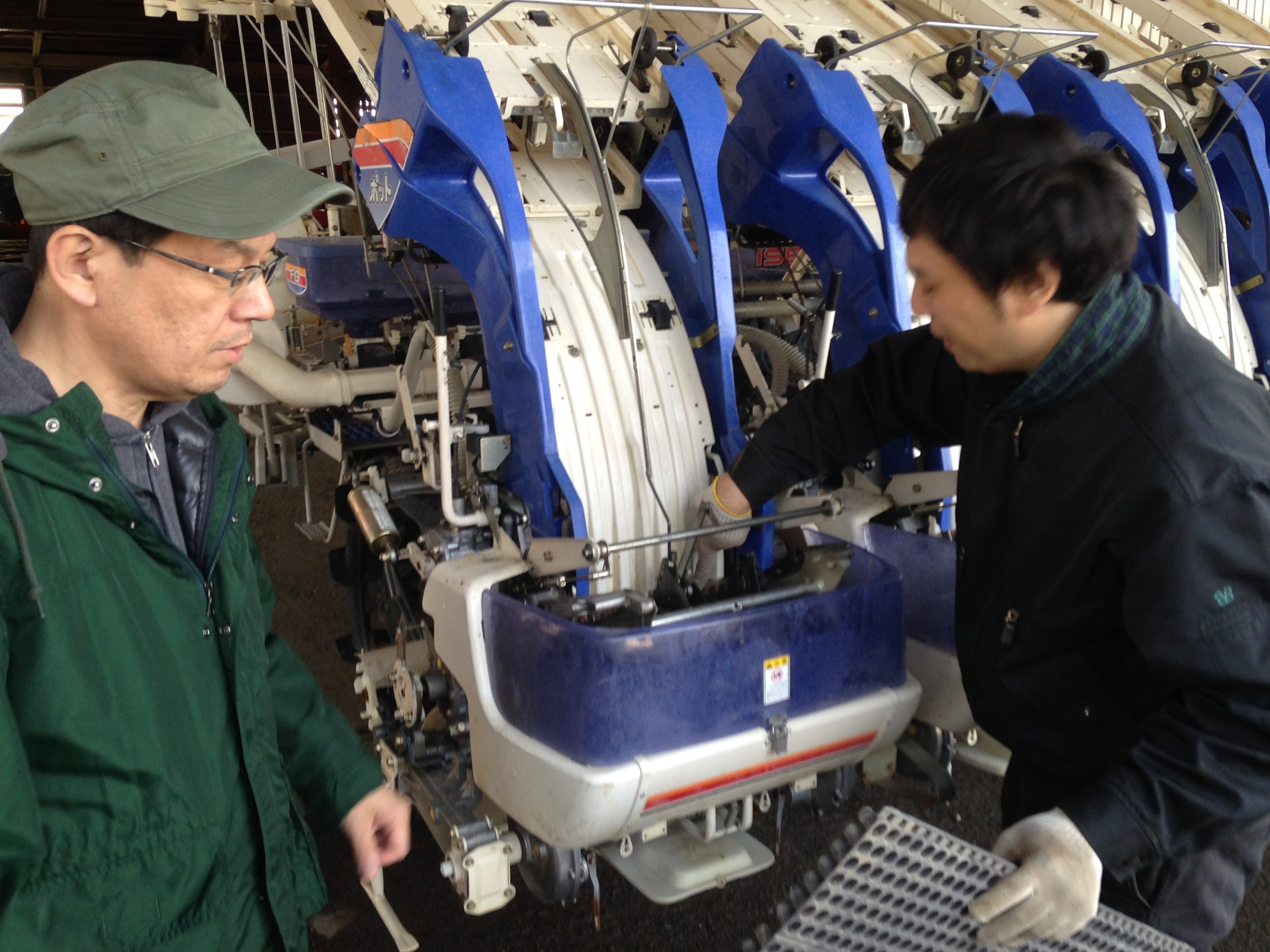 Mr. Ashihara, a techinician for JA Hokkaido / Hokkuren in Iwamizawa shows the mechanism of a "pot-type" rice transplanter to me and Takehiro Ono.