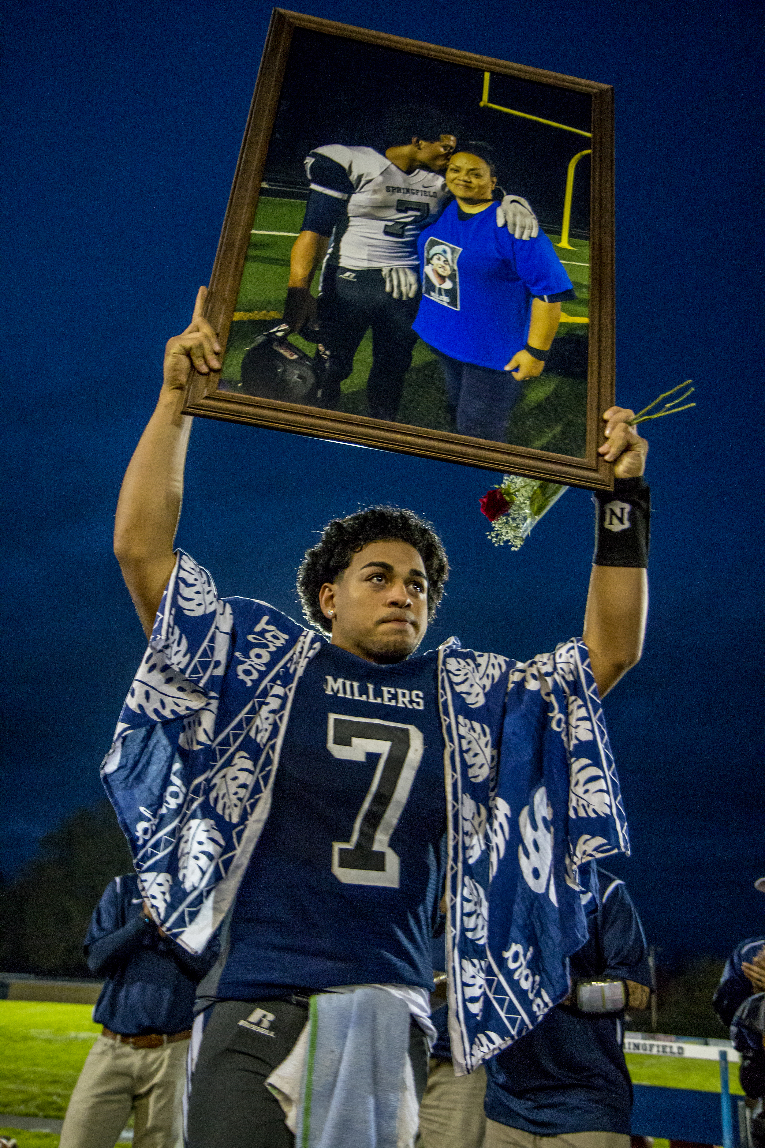  Nick Ah Sam holds up a picture of his mother Margie at a football game at Springfield High School. His mother past away just days before the game. Within the first few minutes of the game, Ah Sam would take off on a long run to make a touchdown, a f