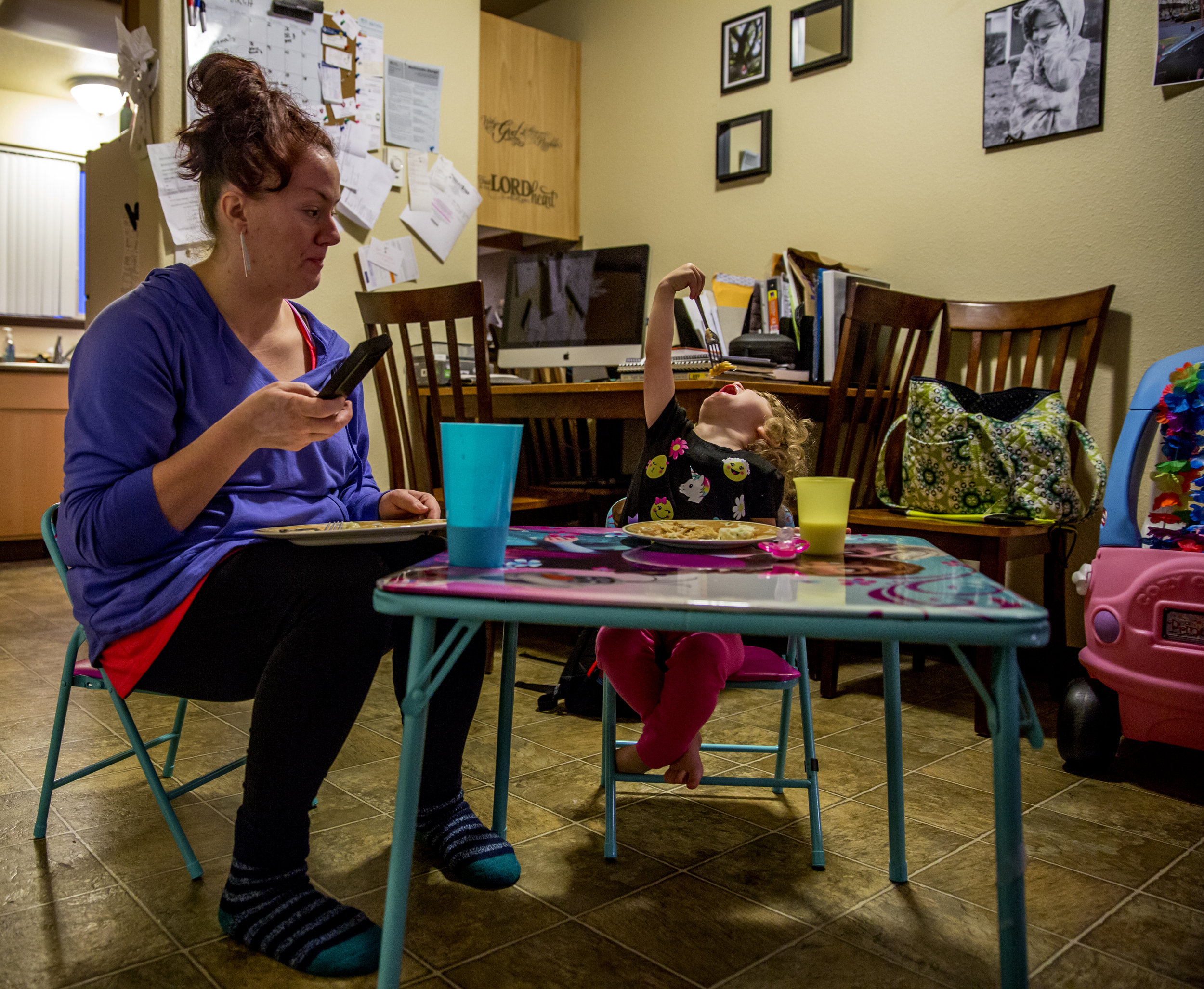   Sarah temporarily turns off the TV to get Suzanna to take a bite. Each night, Sarah and Suzanna eat dinner on a small plastic folding table. The two have lived in their Eugene apartment since Sarah completed the sponsor's program about 8 months ago