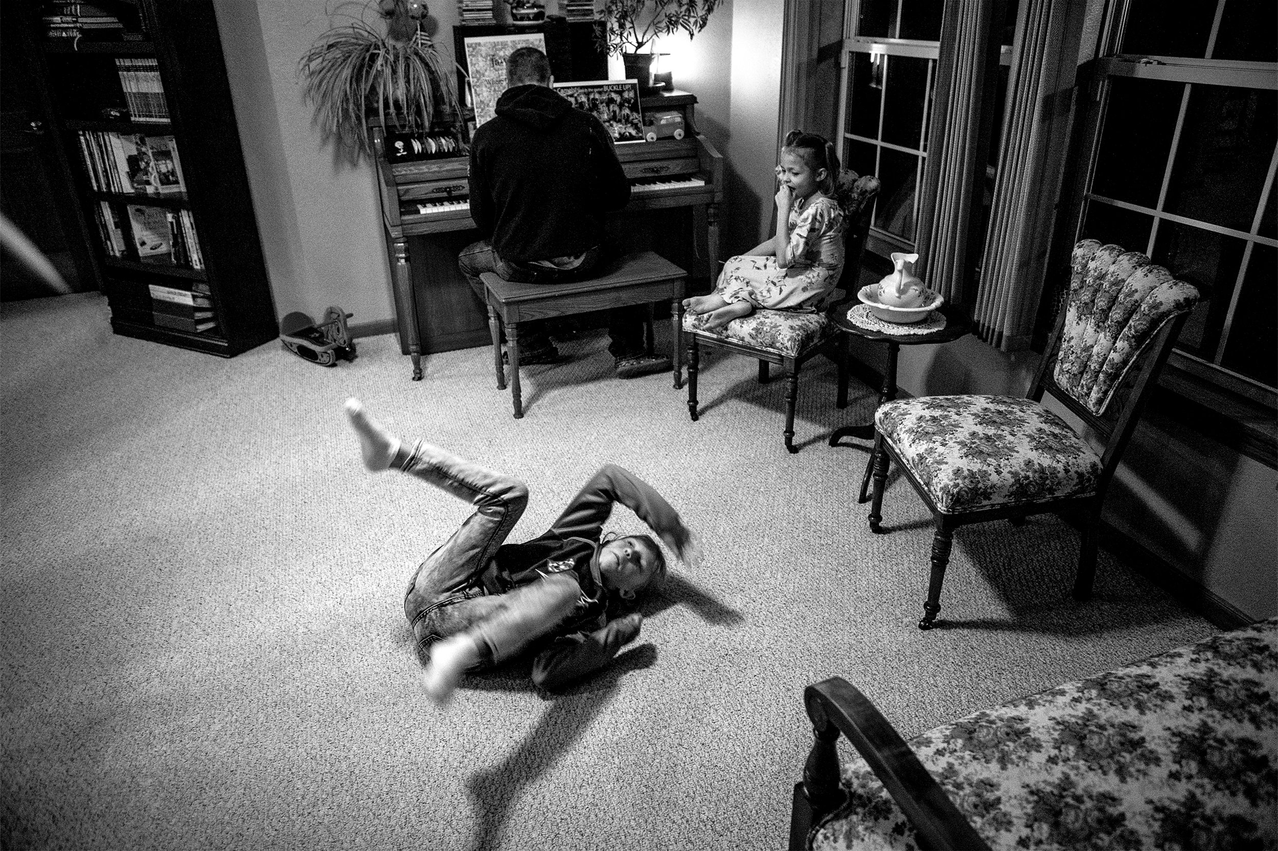  Natalia, 11, rolls backwards across the floor after an attempted sneak up on Derrick Mitchell on the piano, as Leila Pfeil, 9, looks on, during a family get-together on Wednesday, Jan. 9, 2019. Derrick and his wife are looking to adopt three kids, i