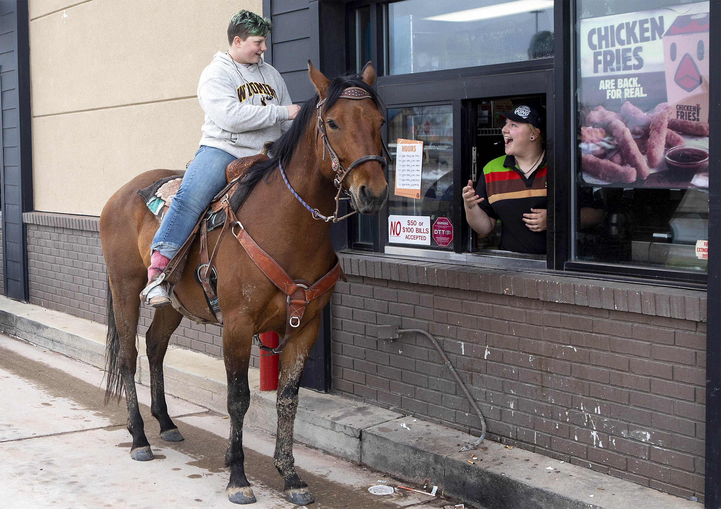  Kristie Laatsch reacts as Dana Blaszkowski, 17, rides her 5-year-old horse Ike up to the Burger King drive-thru window on Thursday afternoon. Blaszkowski decided to take a more rural method of transportation from her home in Rozet to class at Thunde