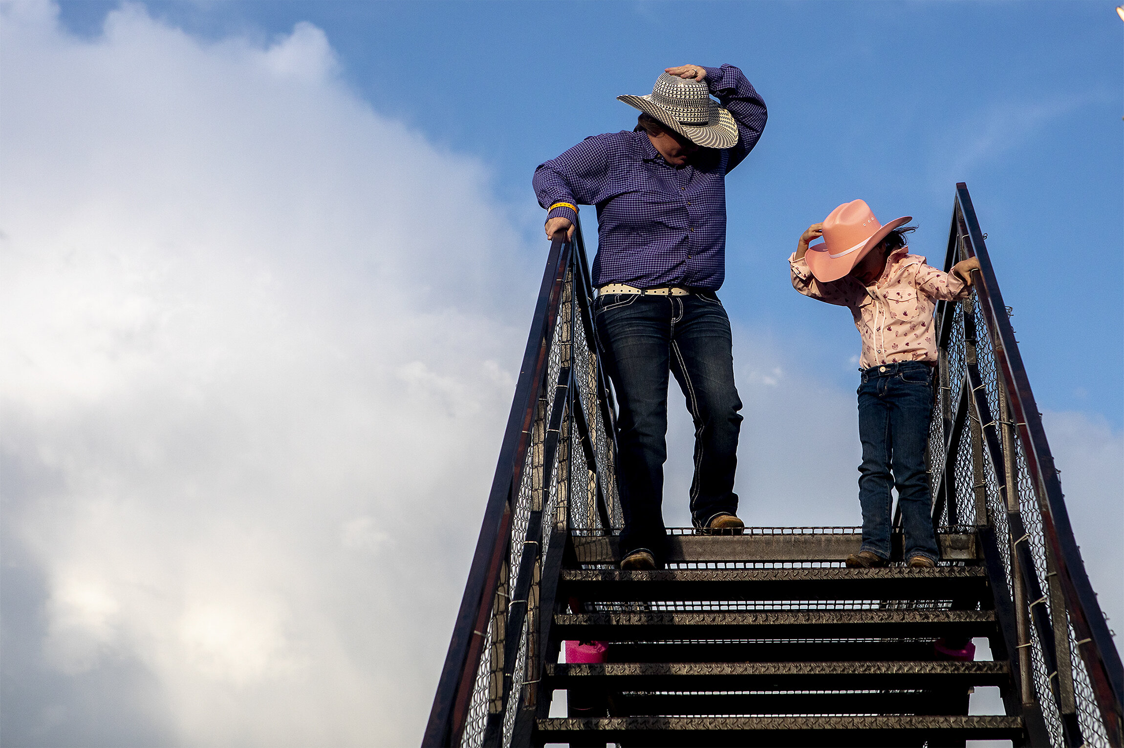  Sunny Welsh and Ava Ritthaler, 6, hold their hats down amidst strong winds threatening to steal them away. Rain clouds loomed in the distance on Friday evening, June 7, 2019, but the rodeo was spared some wetness in exchange for dust in the eyes. 