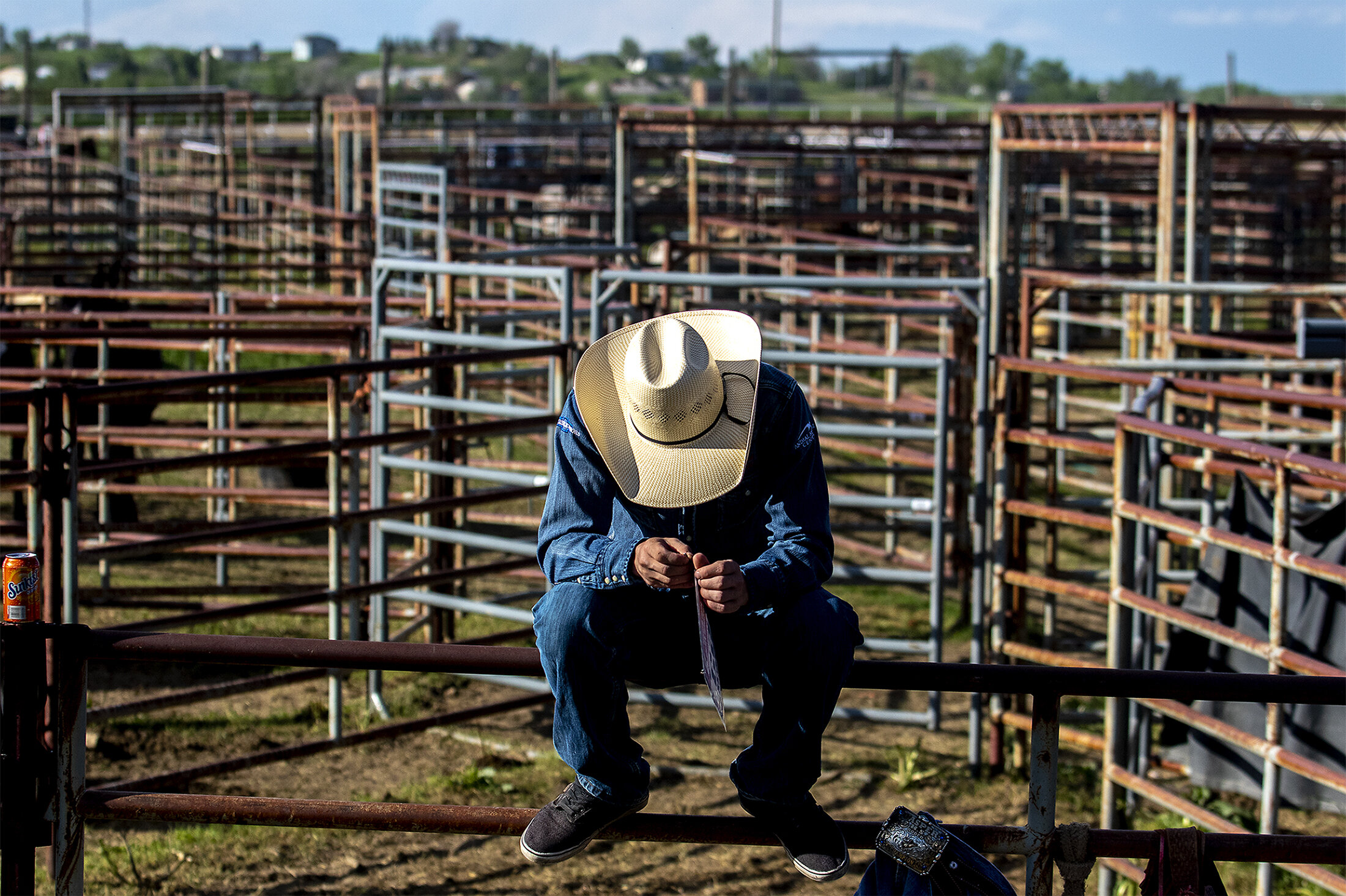  Wyatt Phelps sits atop a fence messing with his number amidst a sea of iron fencing designed to keep the animals in before competition on Friday, June 8, 2019. 