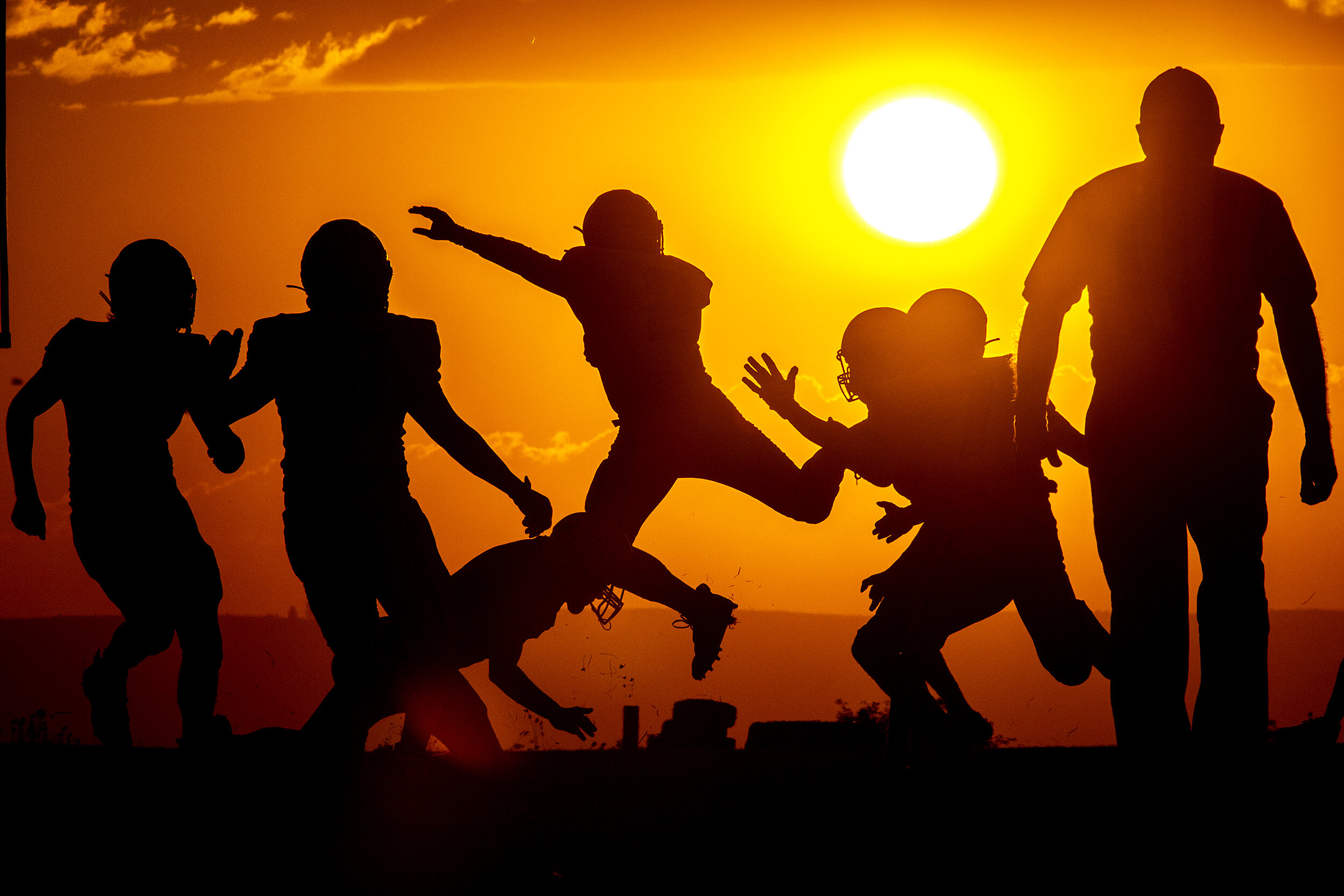  Moscow wide receiver Leon Hutton goes into the air as he tries to avoid Grangeville players framed against the setting sun in Grangeville on Friday night, August 27, 2021. Moscow defeated Grangeville 16-8. 