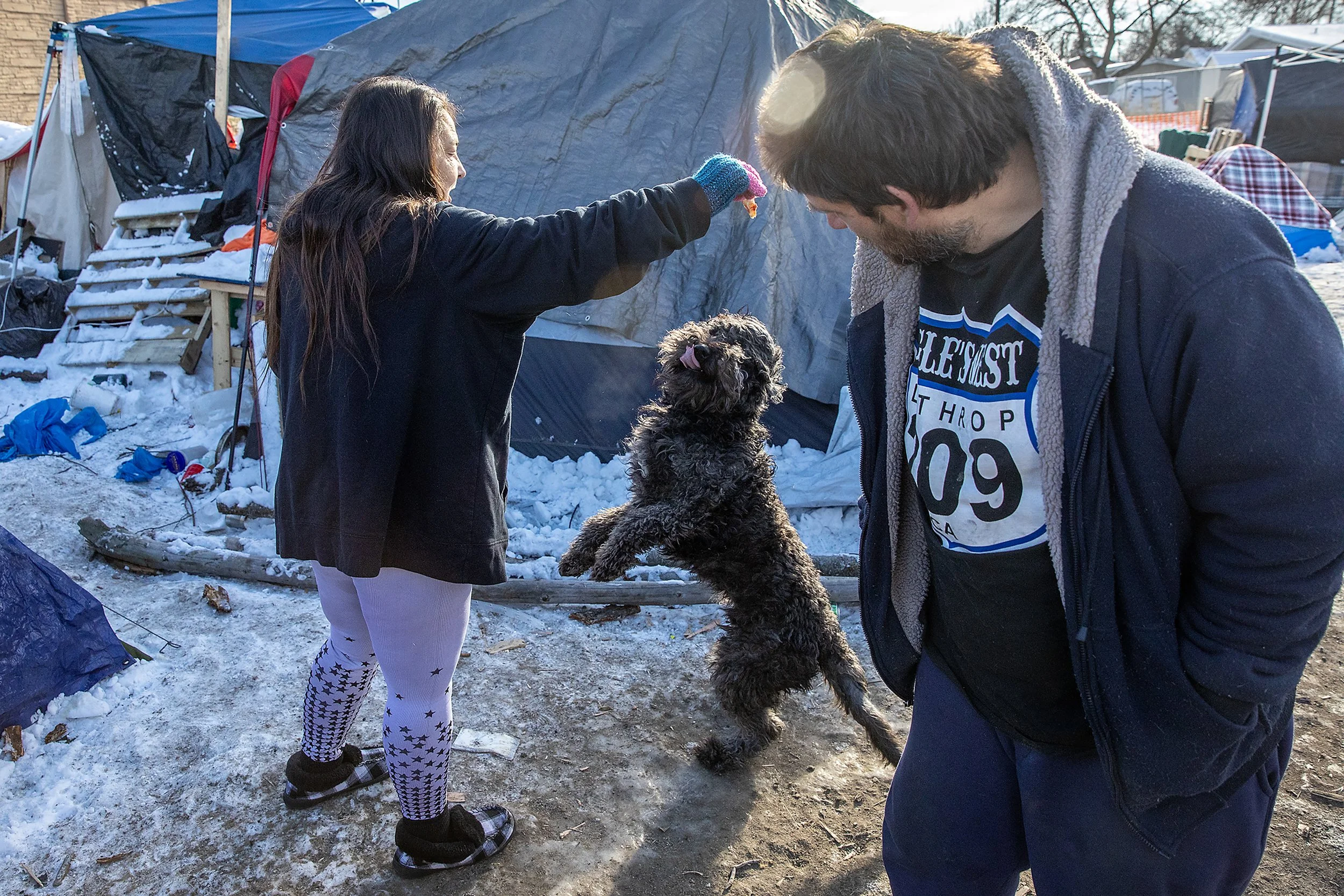  Nancy Caskey holds pizza crust up for her dog Moose as Scott Darrington looks on Tuesday, Jan. 15, 2024, at the homeless camp in Clarkston. Several residents, including Darrington, become the de facto leaders of the group that watched out for others