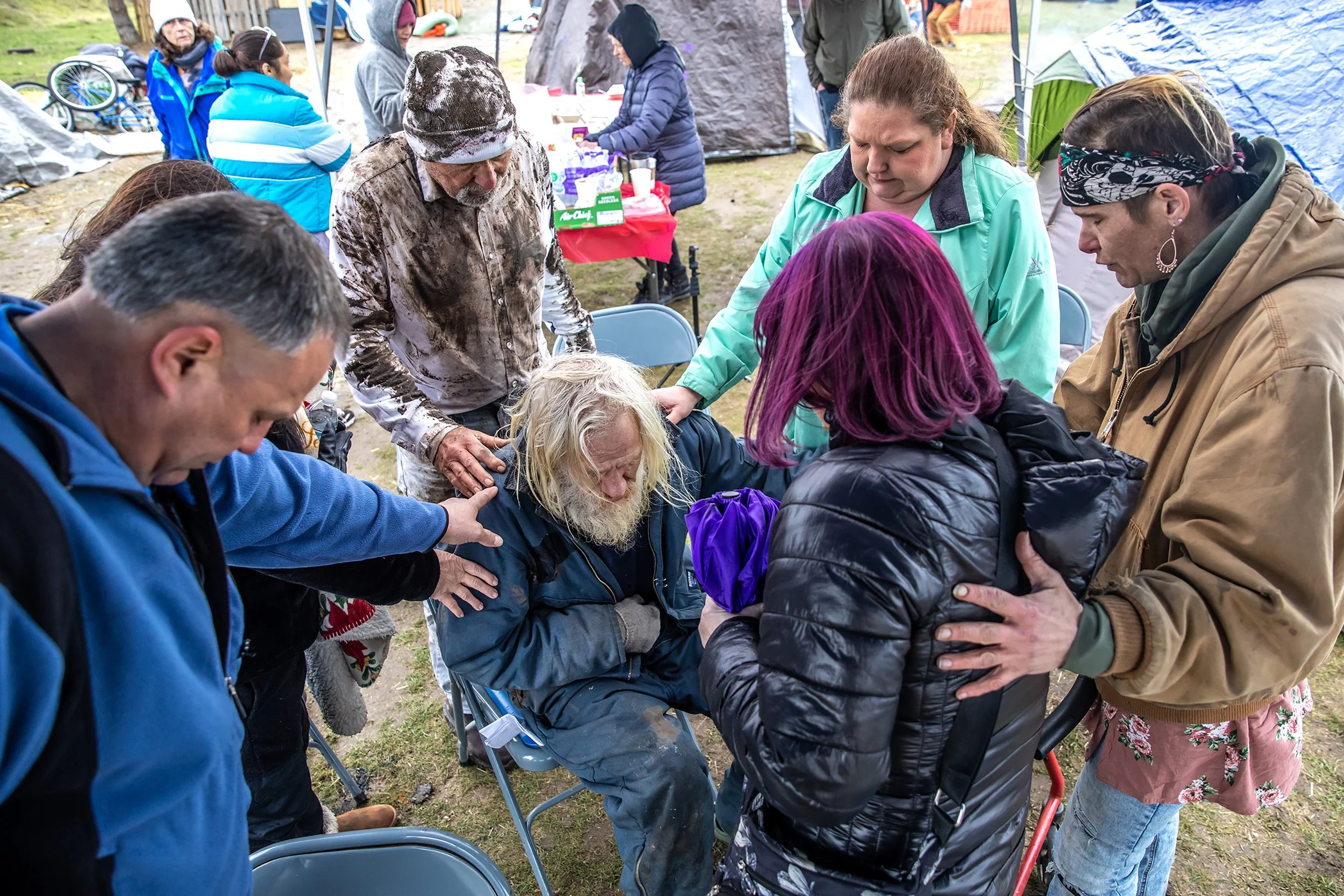  Pastor Nick Hasselstrom, center top, and others place their hands on Walter, an older resident of the homeless camp, as they pray following a Sunday sermon by Hasselstrom at the camp, Sunday, Feb. 11, 2024, in Clarkston. Following the news that the 