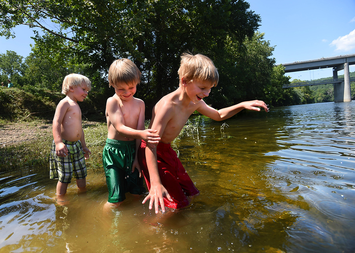 Cody Hales, 4, (center) grabs onto his brother Christopher, 8, (right) as they stumble over rocks while wading into the James River, determined to catch some fish during the James River Transportation Festival. “We wanted to show them the beauty of Virginia,” said Caroline Wilson, whose grandchildren are visiting from North Carolina.