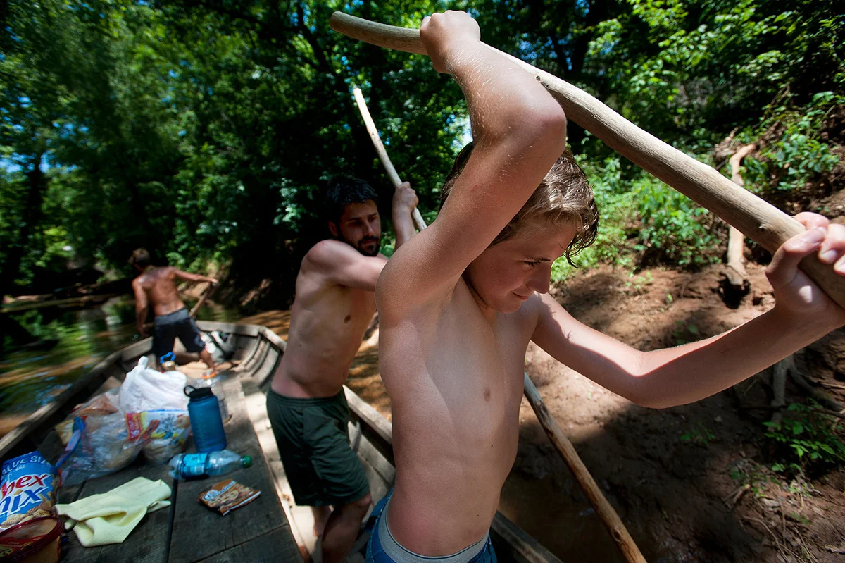John Morton uses a long wooden pole to help shift the Mary Marshall out of shallow water in a tributary of the James River.