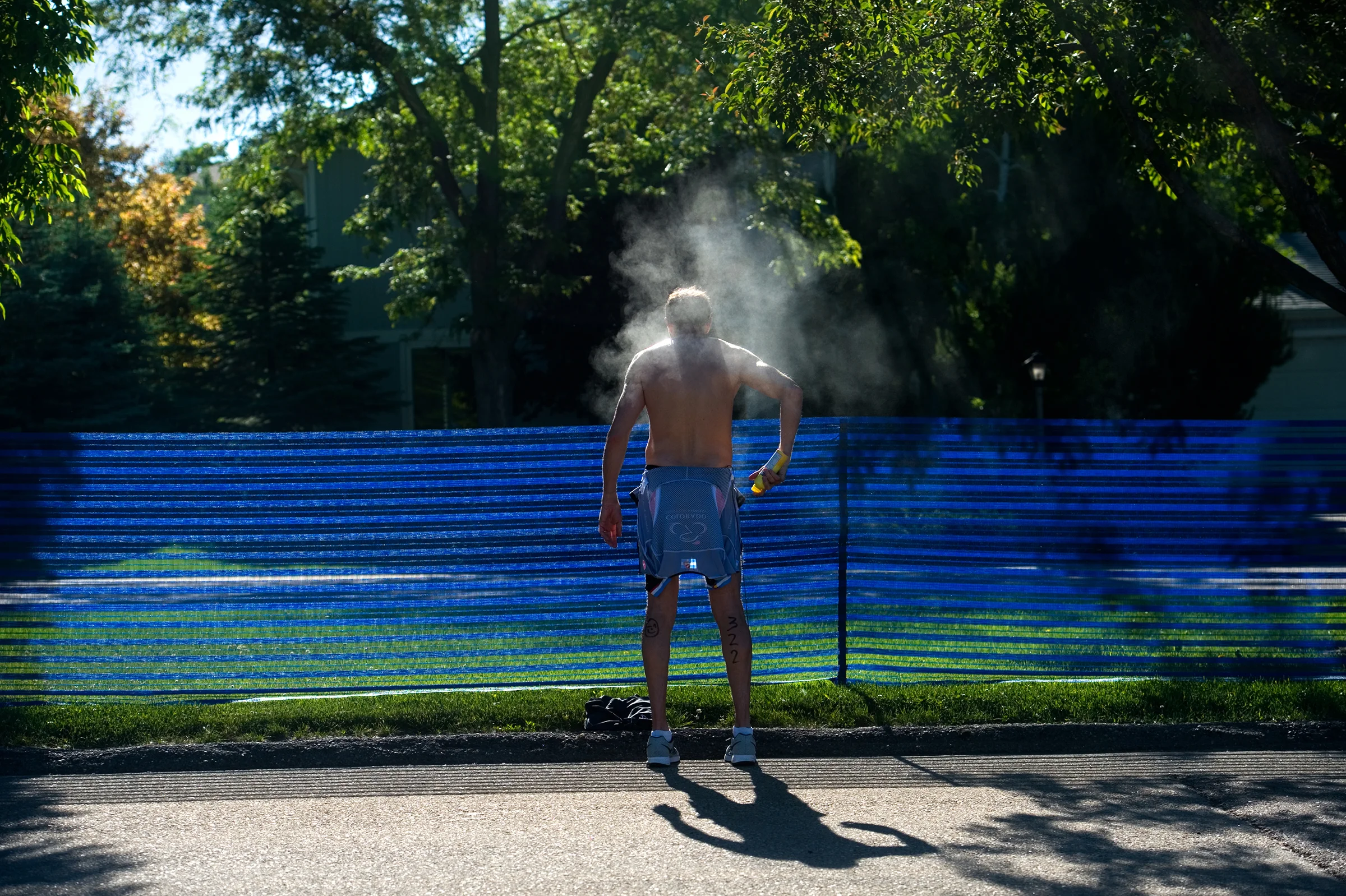 Thomas Beal sprays himself with sunscreen before beginning the biking portion of the Longmont Triathlon at Centennial Pool in Longmont, Colo. 