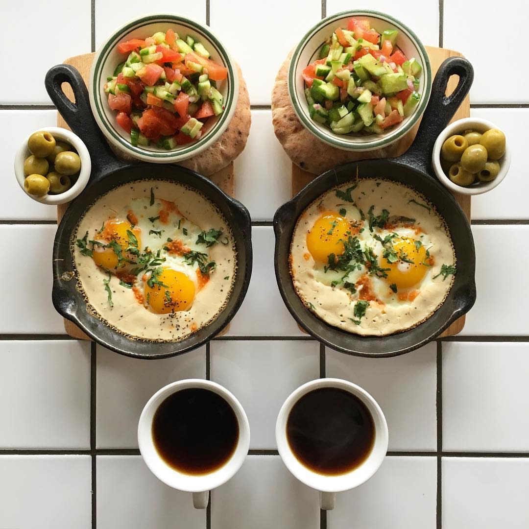 Eggs siniya (eggs cooked in tahini and chilli) with pita, Israeli salad, olives and black coffee. PC: @symmetrybreakfast