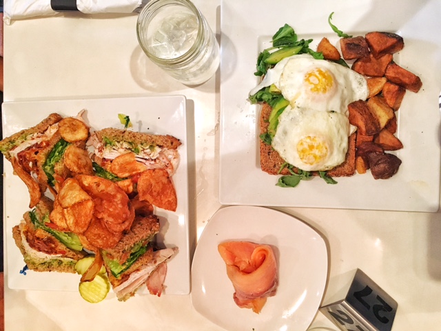 Turkey club sandwich with chips, avocado toast with 2 sunnyside eggs, potatoes and smoked salmon on the side
