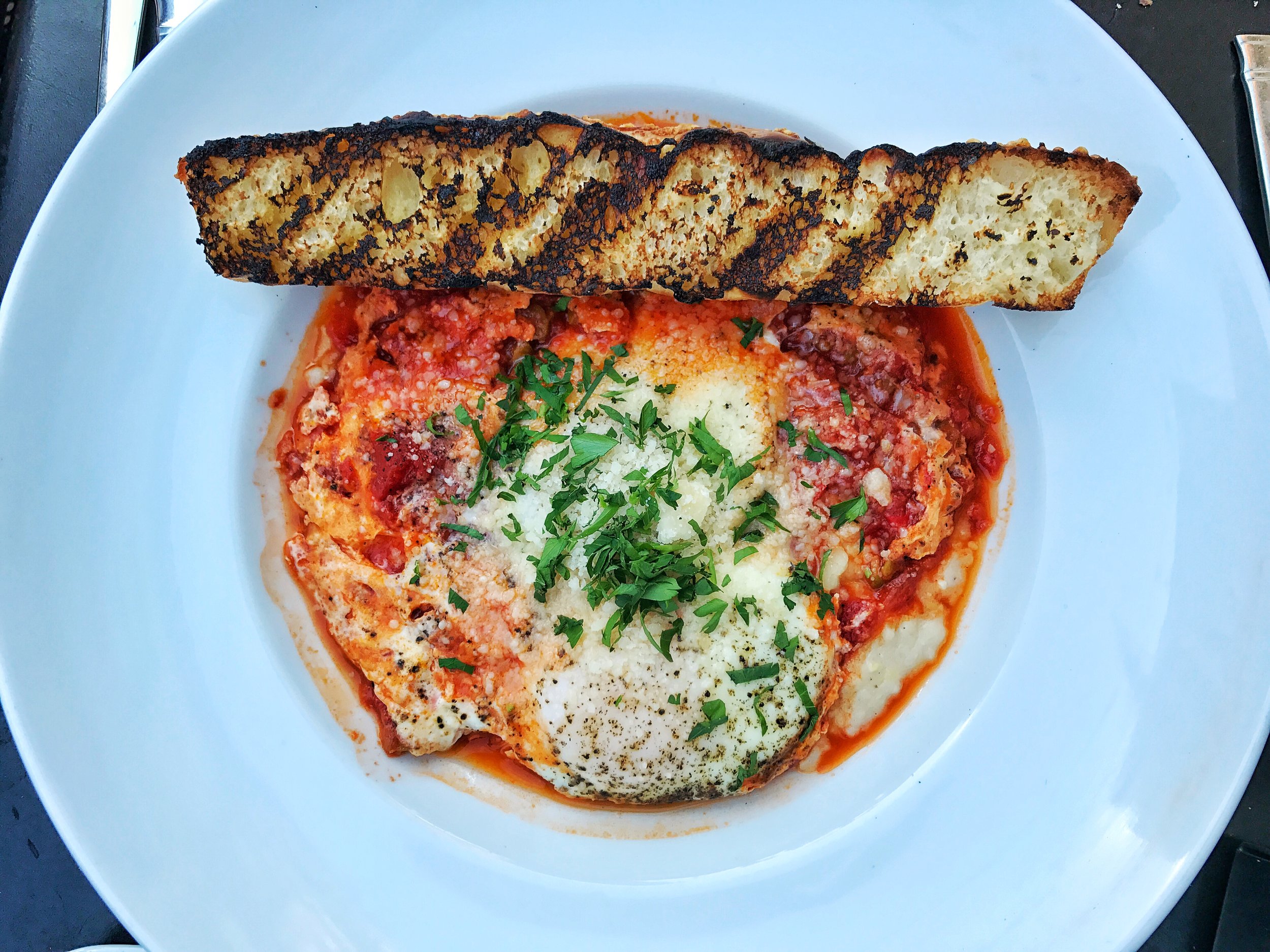 Eggs in purgatory- goat cheese grits, tomato olive ragu, baked eggs and focaccia 