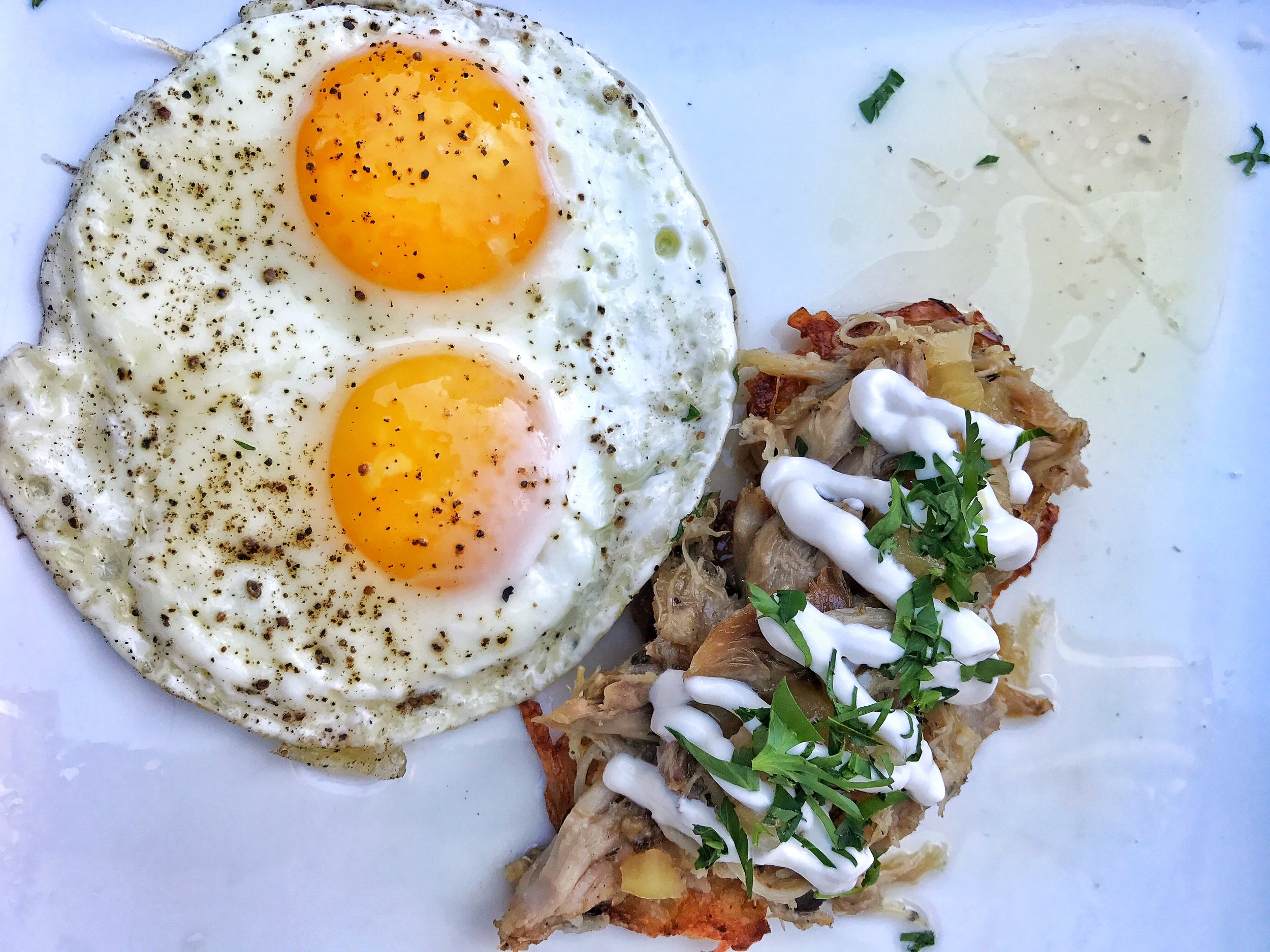 Chicken confit and potato latkes with sunnyside up eggs and apple thyme jam with sour cream on top
