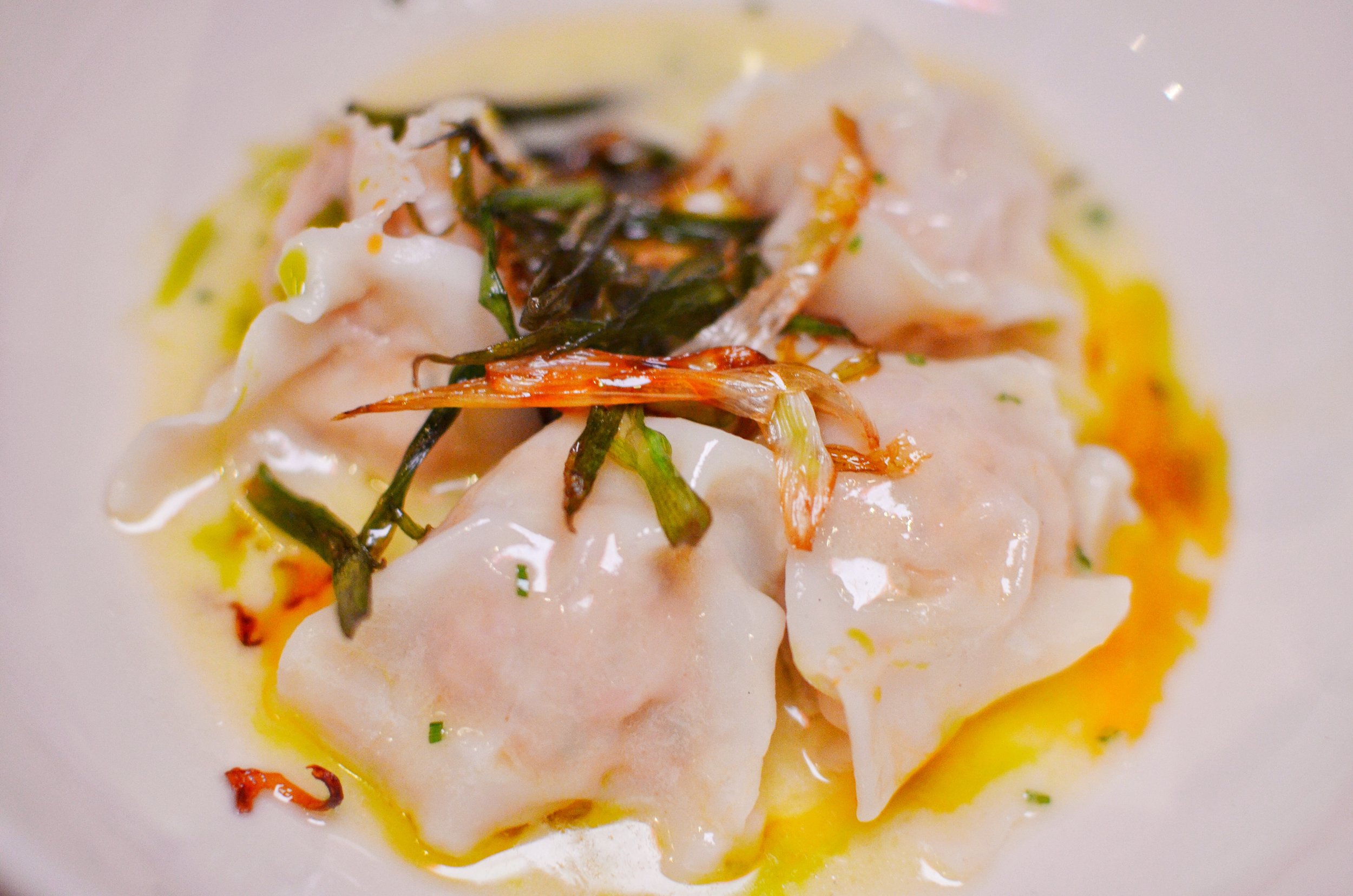 Shrimp pillow dumplings in ginger butter, scallions and herb oil