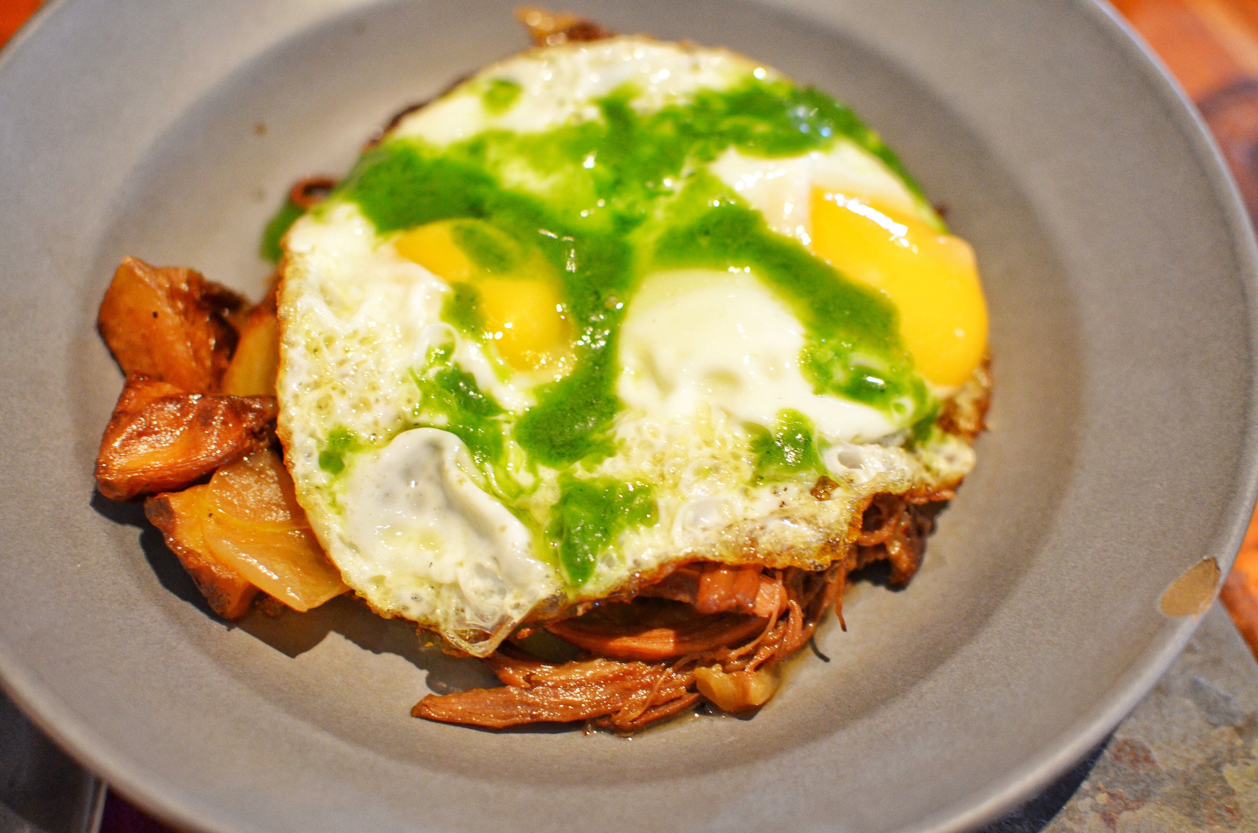 Grass fed beef hash with yukon potatoes, two fried eggs, salsa verde and cramalized onions
