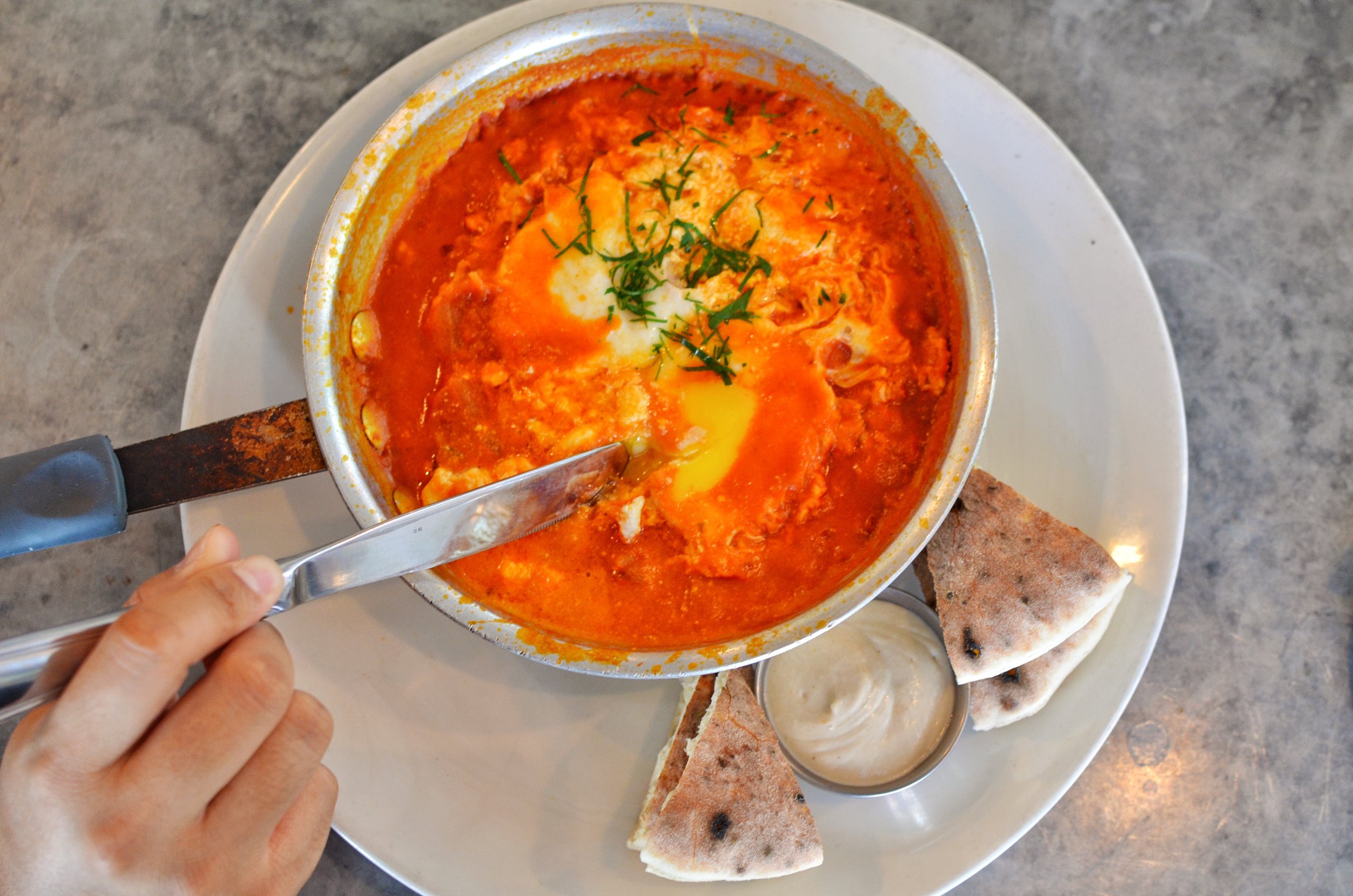 Shakshuka- Baked eggs and a spicy tomato onion sauce, tahini