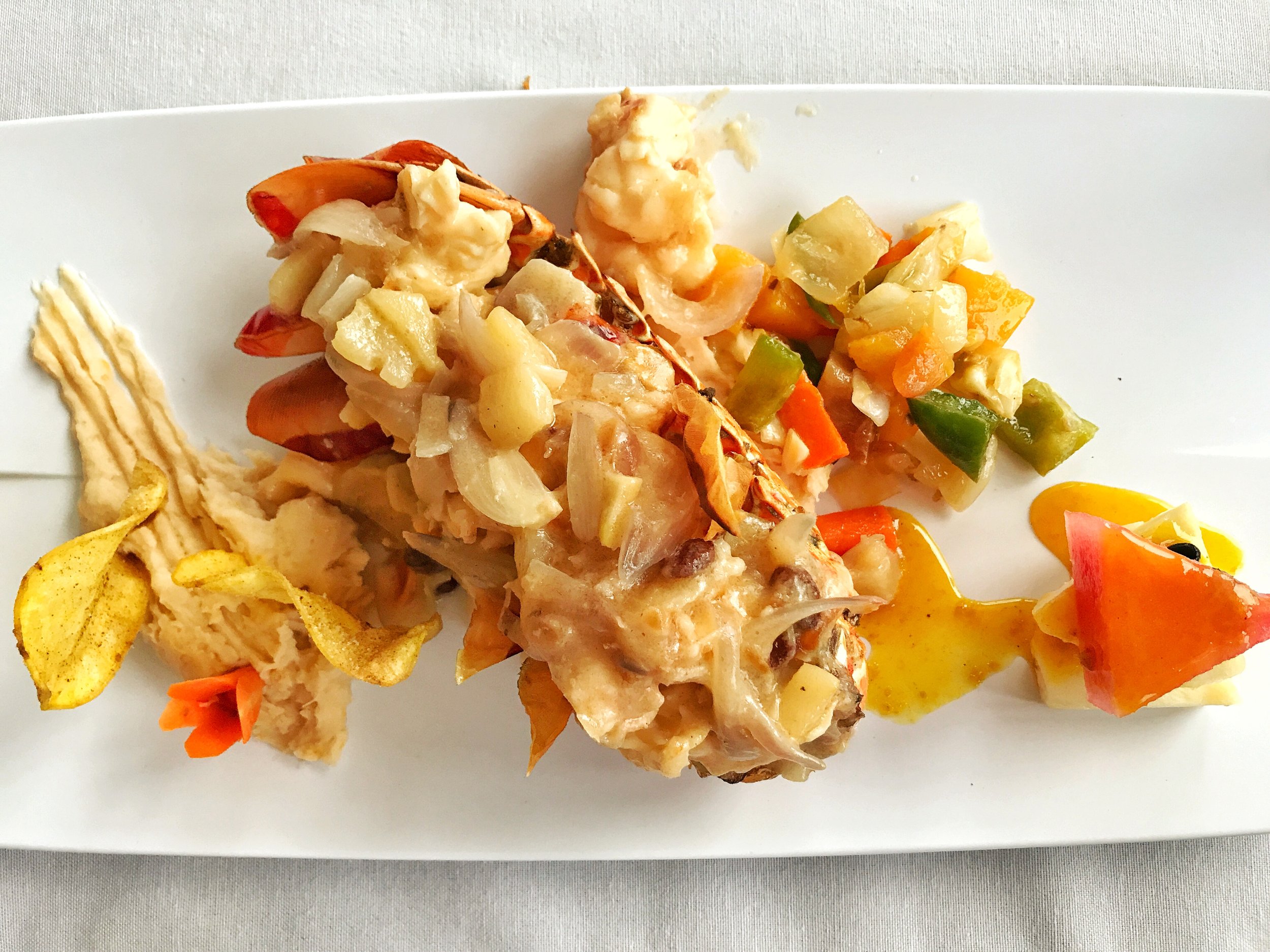 Broiled lobster cooked in Rum sauce with a plantain puree and vegetables on the side