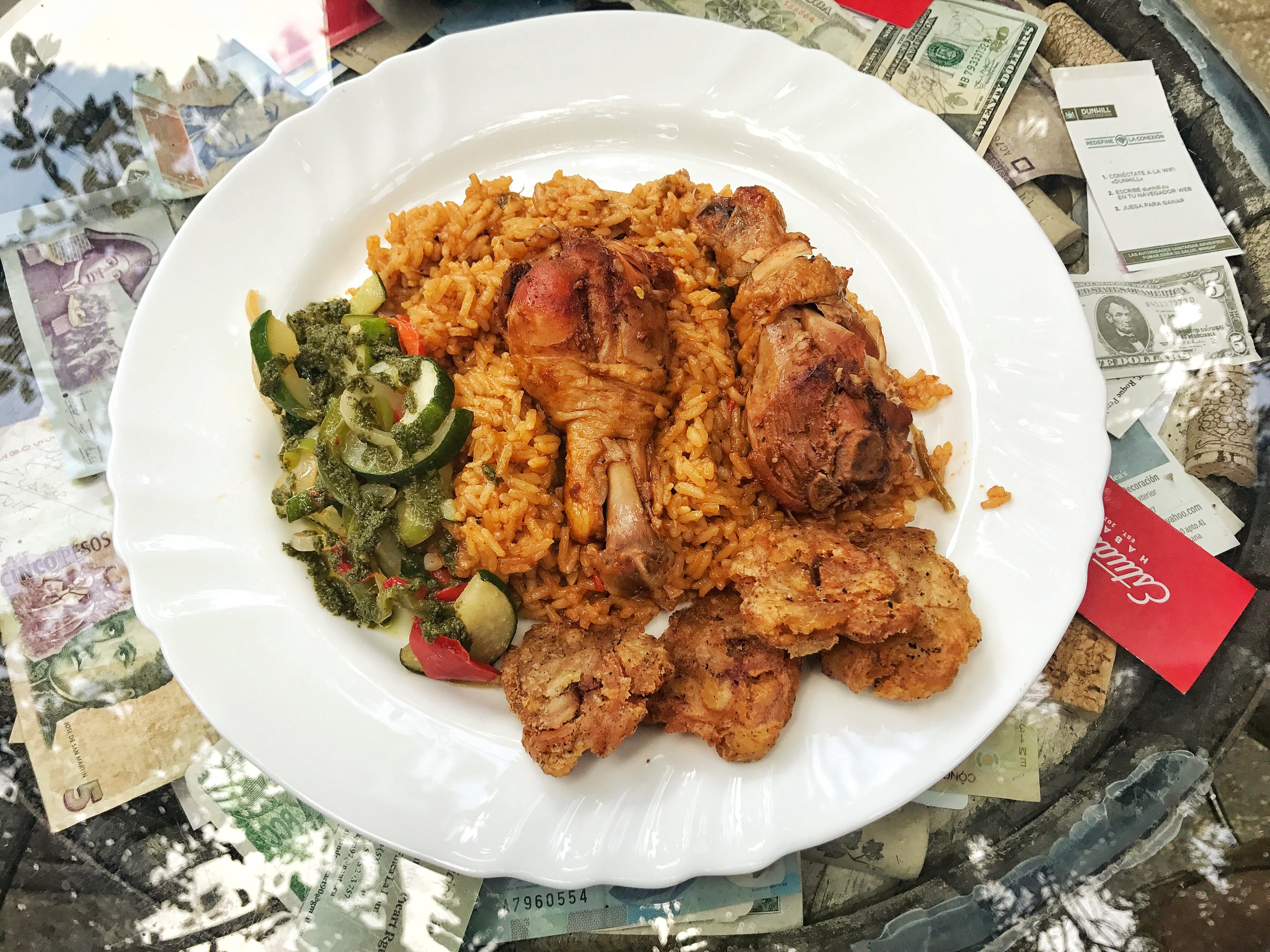 Roasted chicken legs with tostones, paella like rice, vegetables with a chimmichuri sauce 