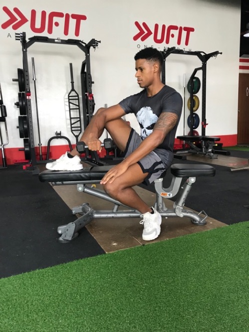 1. Holding a dumbbell in one hand, rest you elbow on your knee, with your arm pointed downwards.