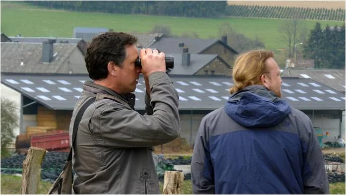 Photo : Vincent Leirens (à gauche) et Alain De Broyer, deux des ornithologues de l’équipe d’Aves, cherchant à localiser un nid de Milan royal en bordure d’un site Natura 2000 de la Province de Namur (photo : Rudi Dujardin).