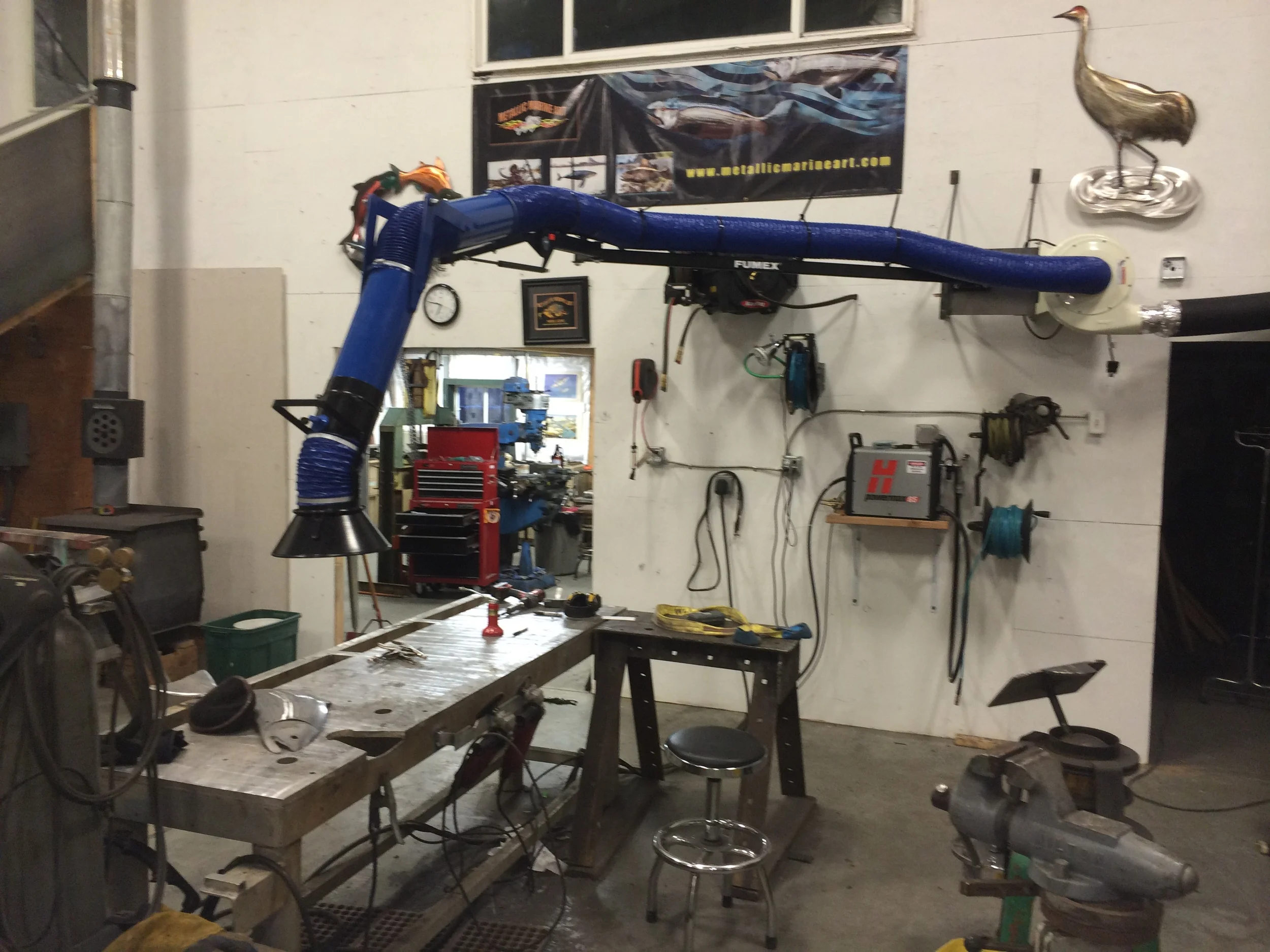 This is the main workstation for welding and buffing. Hose reels for compressed air, filtered air for the mask, oxy acetylene, oxy propane, and 110v power help to keep the confusion to a minimum. The overhead suction keeps the fumes at bay. The plasma cutter is the heart of my operation. This one is a Hypertherm Powermax 65. Its nice to have 3 plasma cutters in the shop, but I'm much more comfortable now that I have four. Yes, I am a tool addict.
