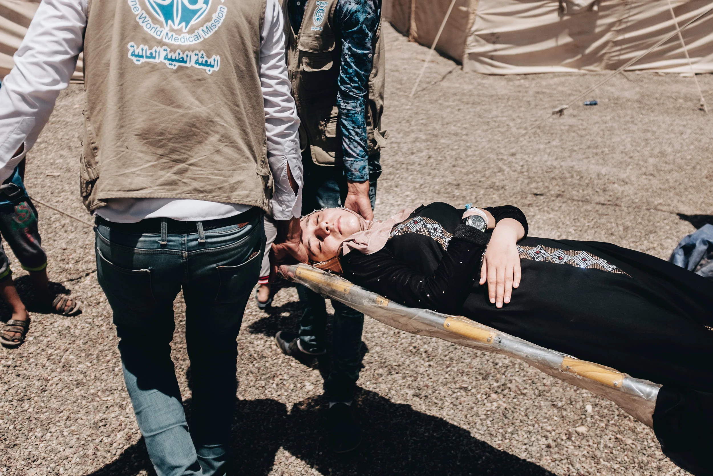 A woman requiering urgent medical attention is taken from her tent to a nearby ambulance by volunteers. Before the ambulance can leave the camp it will undergo a thorough search at the gate by Iraqi security forces to make sure no other residents ar…