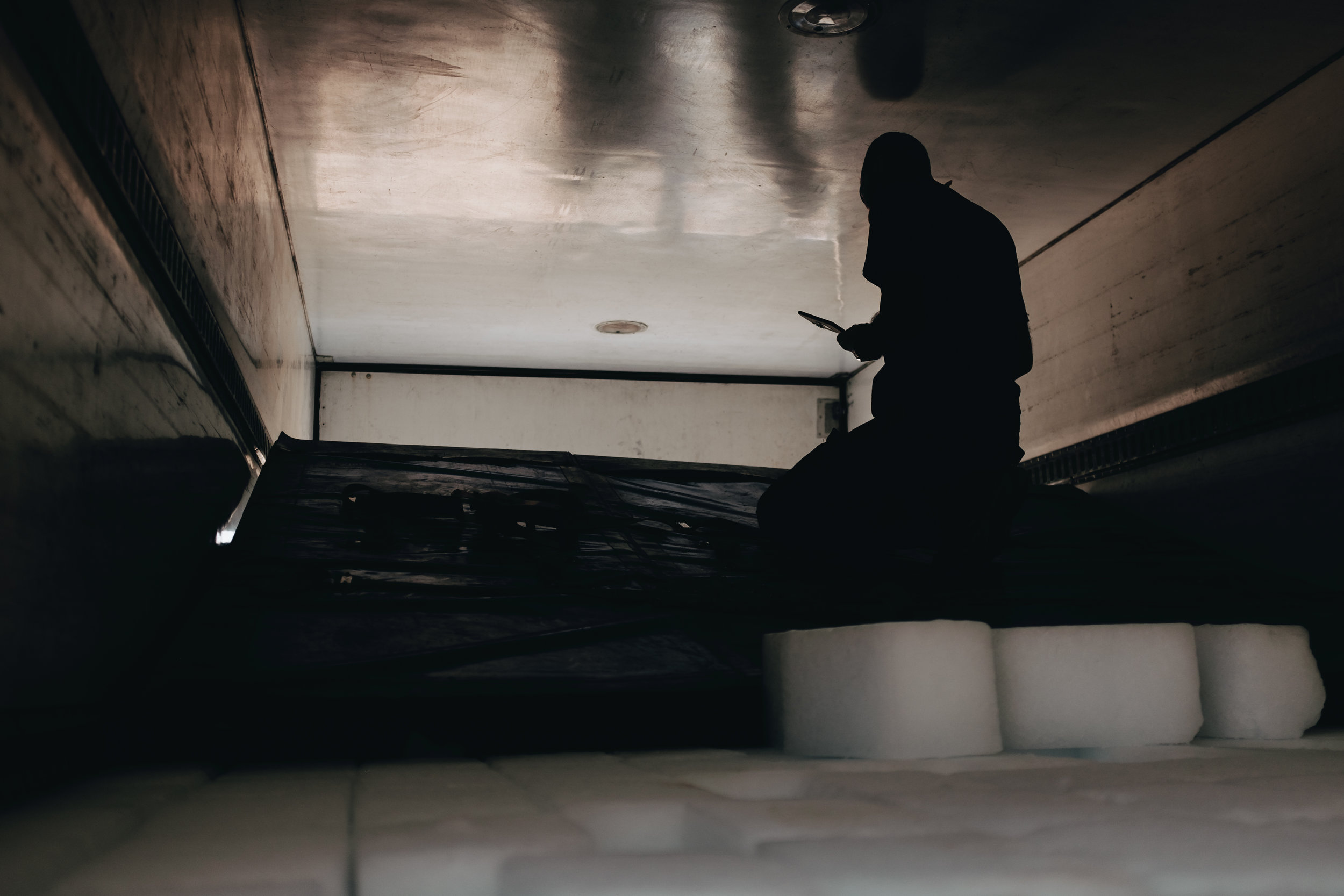 Mohammed, a team leader for the Wasel Tasel team, a local NGO, manages the logistics of aid distrobutions from the back of a refregerated truck containing thousands of blocks of ice to be given to the residents of IDP camps around Mosul.