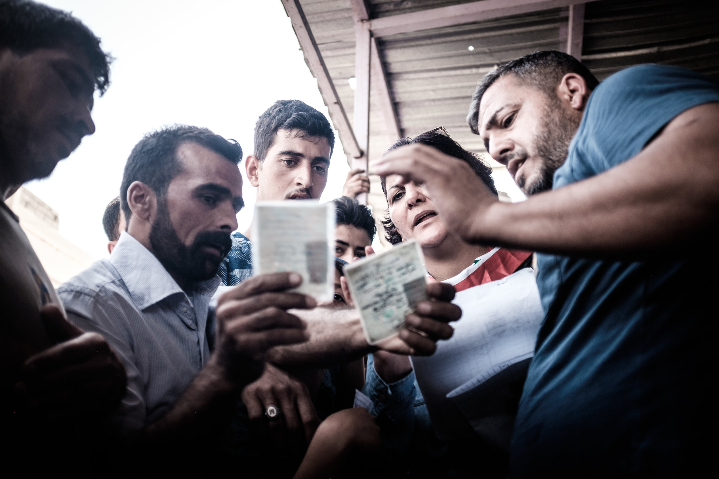 Volunteers from a local NGO check off names of residents from a list against their identification. Once it has been verified that they are indeed a local resident they are issued with tokens which can be exchanged for supplies such as bottled water,…