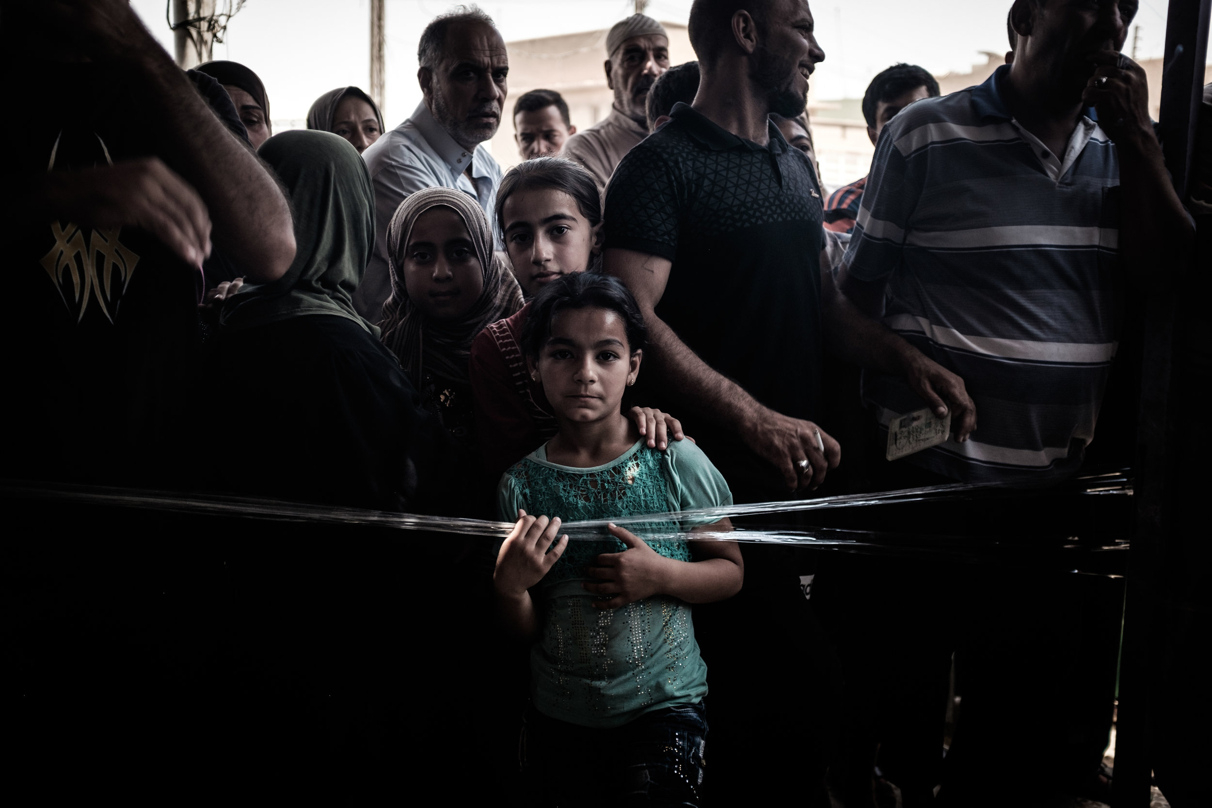 Young girls stand in the crowd as other residents from their neighbourhood tower over them.