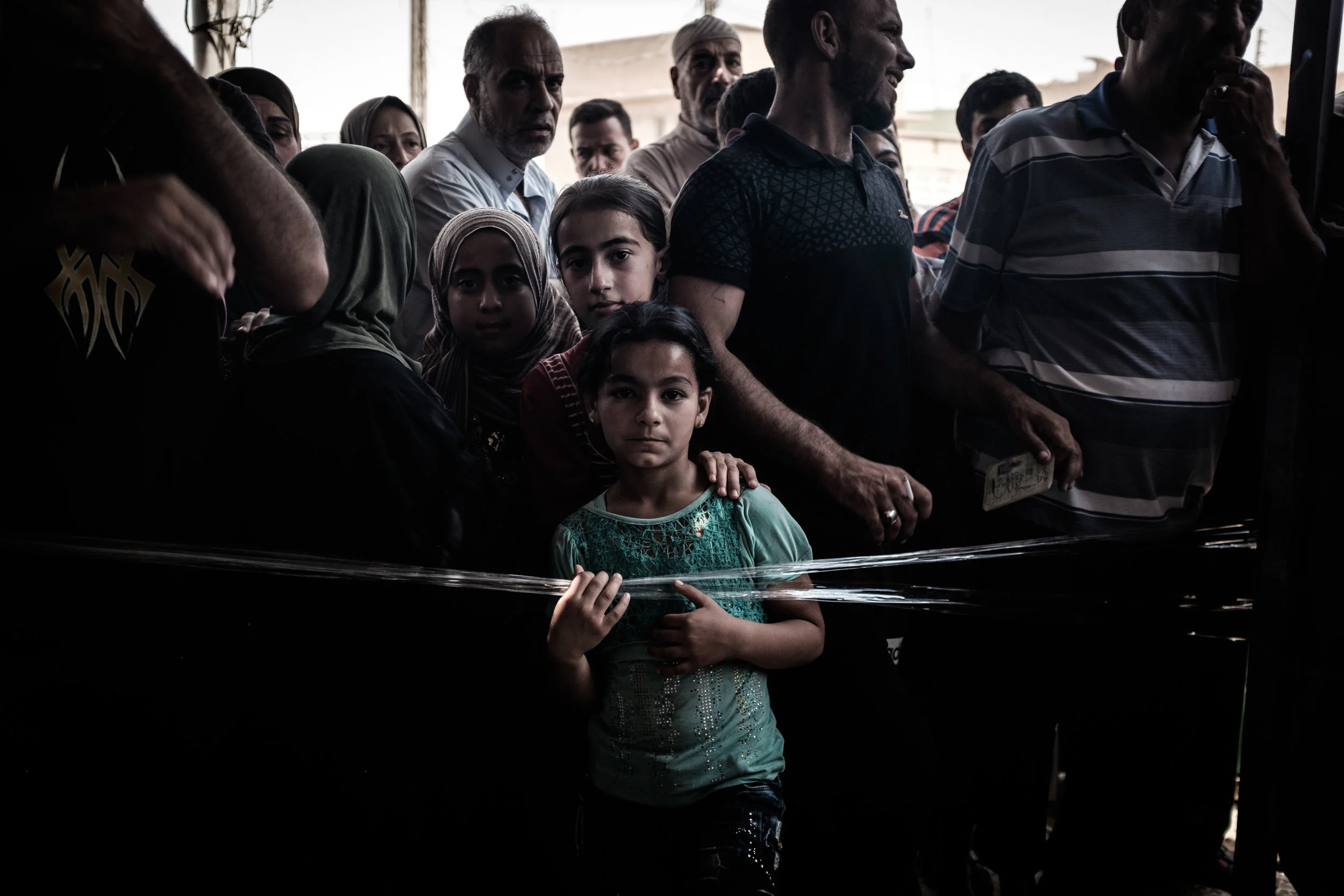 Young girls stand in the crowd as other residents from their neighbourhood tower over them.