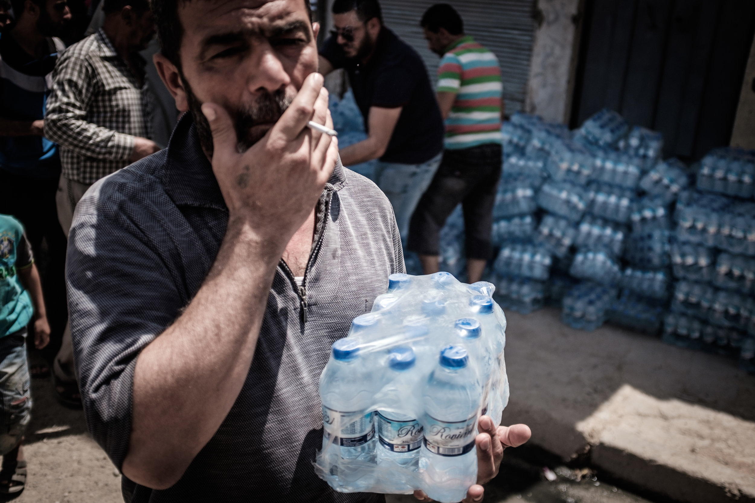 A man carries bottles of water that have been distributed by a local NGO as part of the first distribution of it's kind to this area in a number of weeks