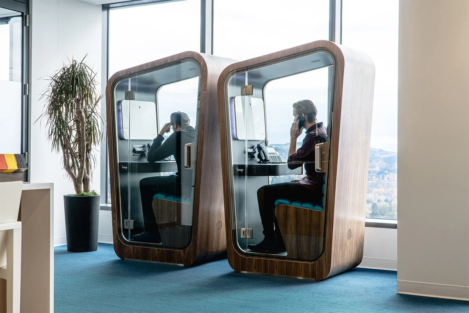 Two-Loop-Solo-Phone-Booths-with-people-talking-on-the-phone-in-them-sit-in-the-pokemon-offices.jpg