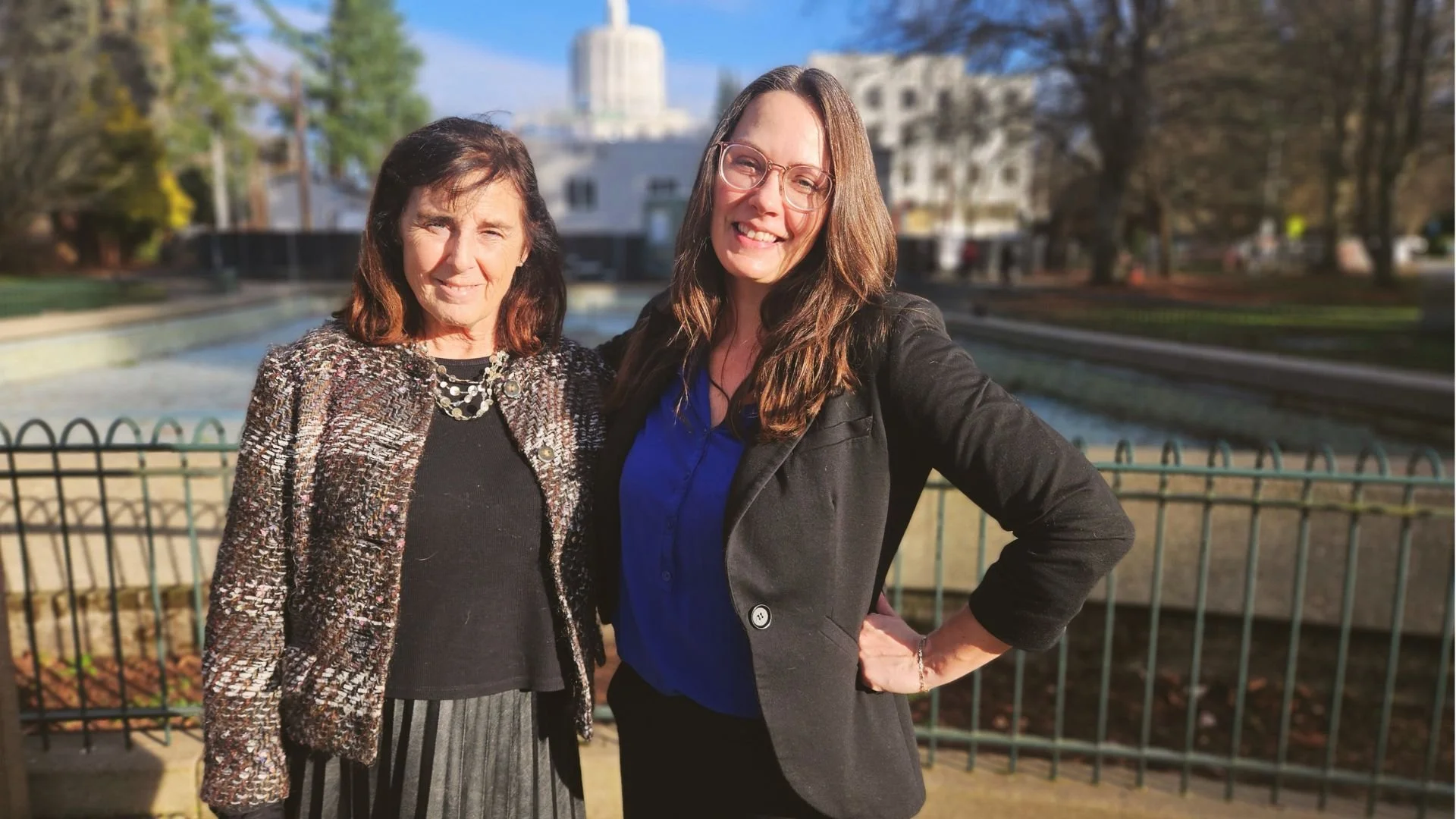 two women in business attire in front of a government building