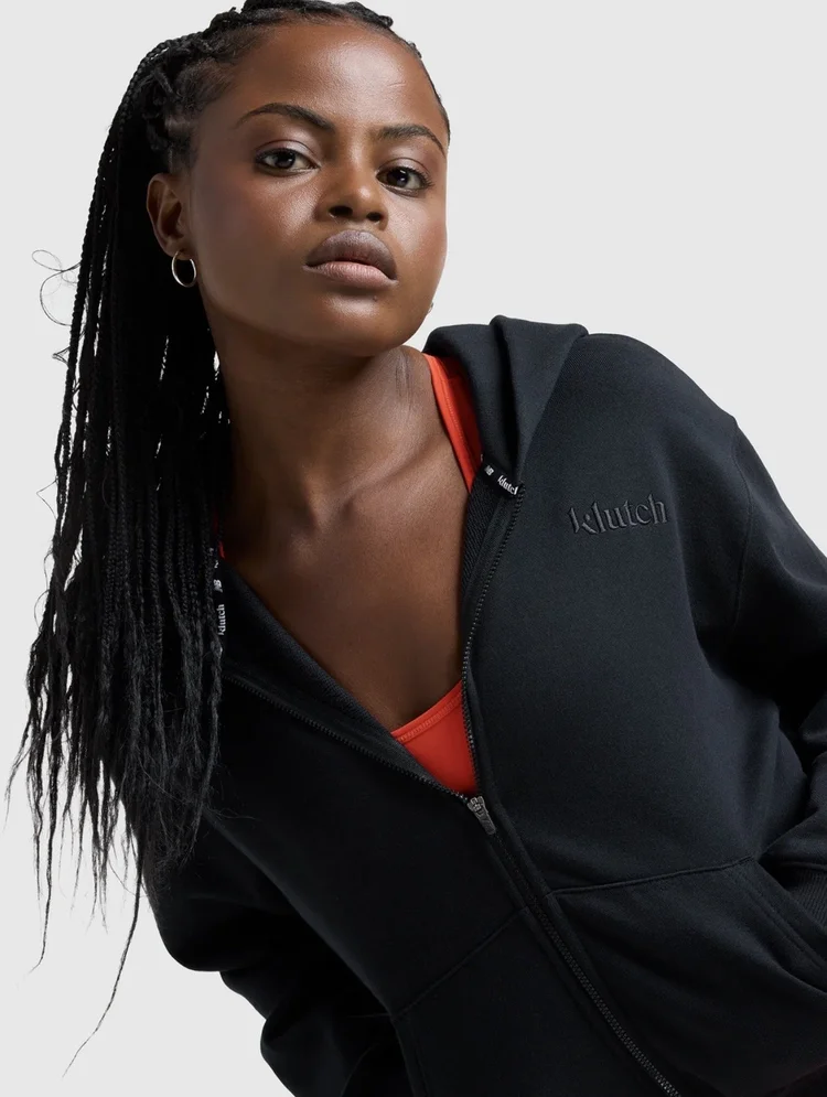 Portrait of a model with long braids in a black athletic jacket with red detailing