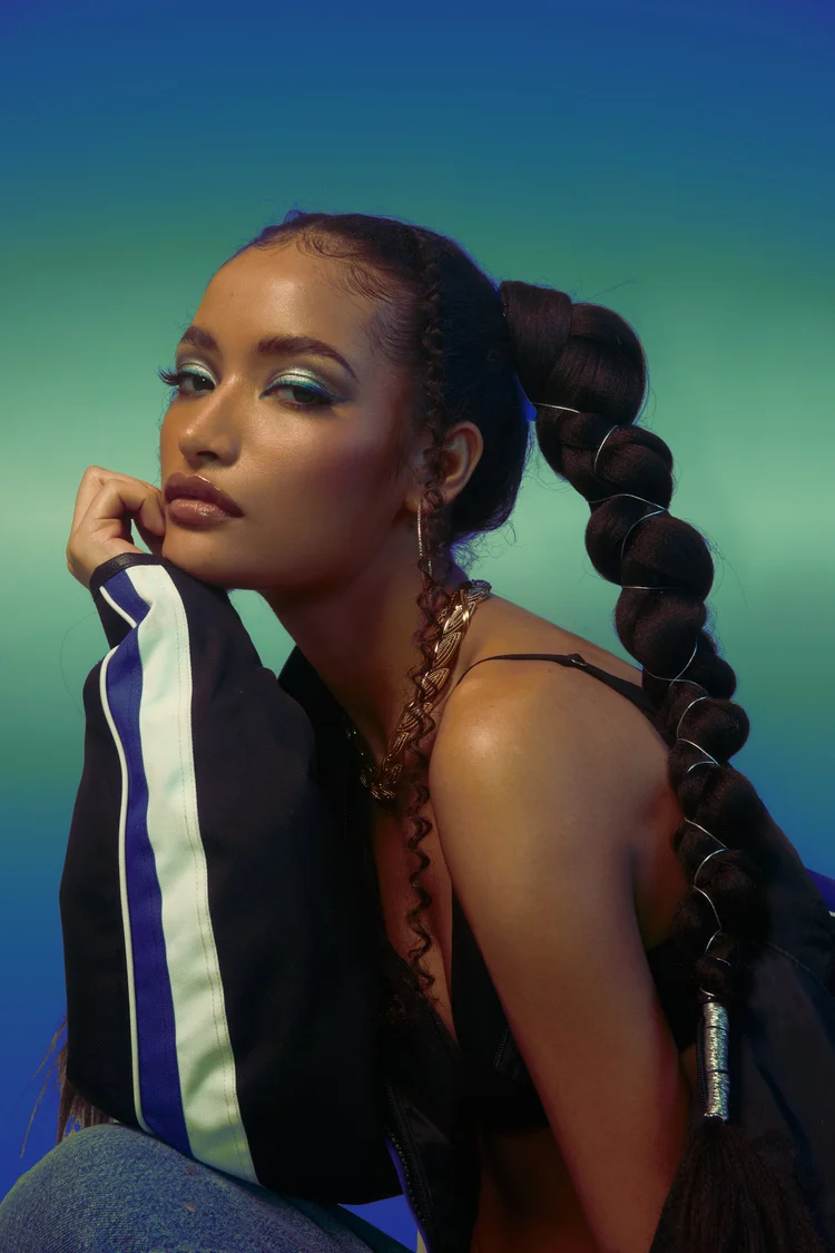 Fashion portrait with sculptural bubble braids and a blue and green athletic jacket