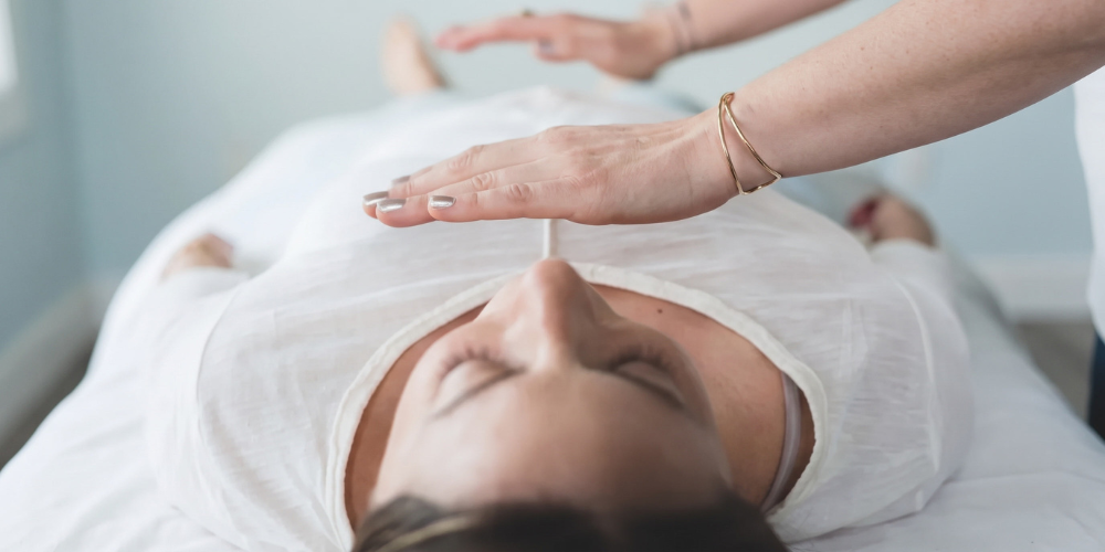Reiki healing session with a practitioner gently placing hands over a client during energy healing.
