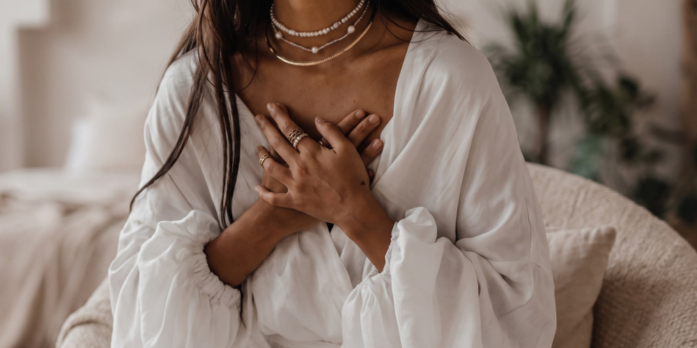 Woman sitting peacefully with her hands over her heart during a mindful self-care or emotional healing practice.