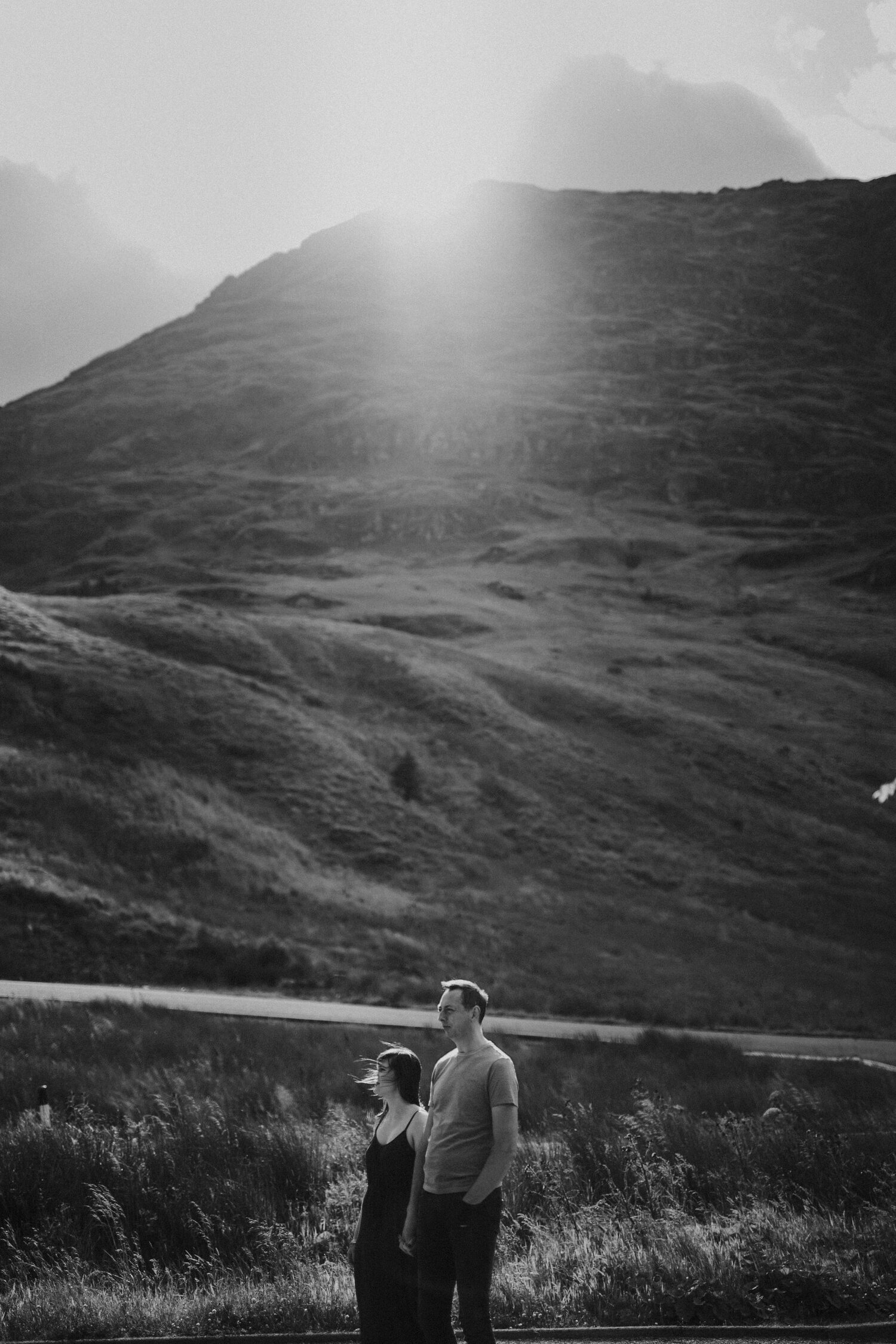 a couple standing in teh mountains during sunset black and white picture