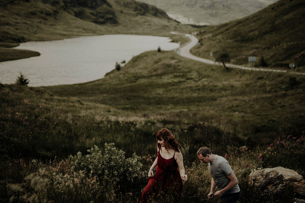  a man and woman hiking in the Scottish Highlands during their engagement photoshoot 