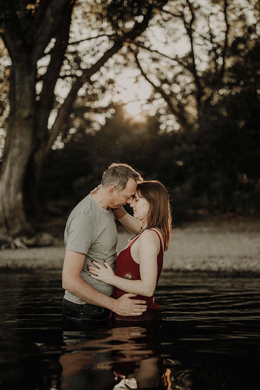  girl and man in a lake kissing during sunset  