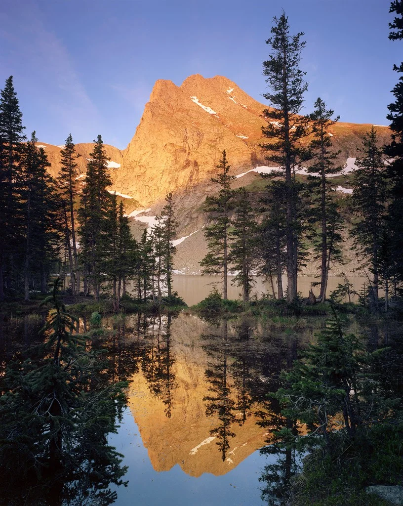 Tijeras Peak reflects in the calm waters of a pond attached to Sand Creek Lake.