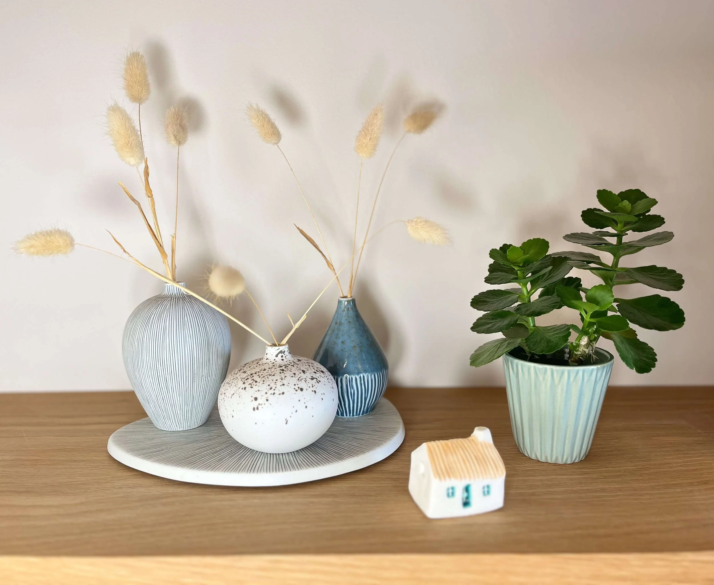 A calming arrangement of small vases with dried grasses and a tiny house ornament — evoking peace and grounding in EMDR trauma therapy