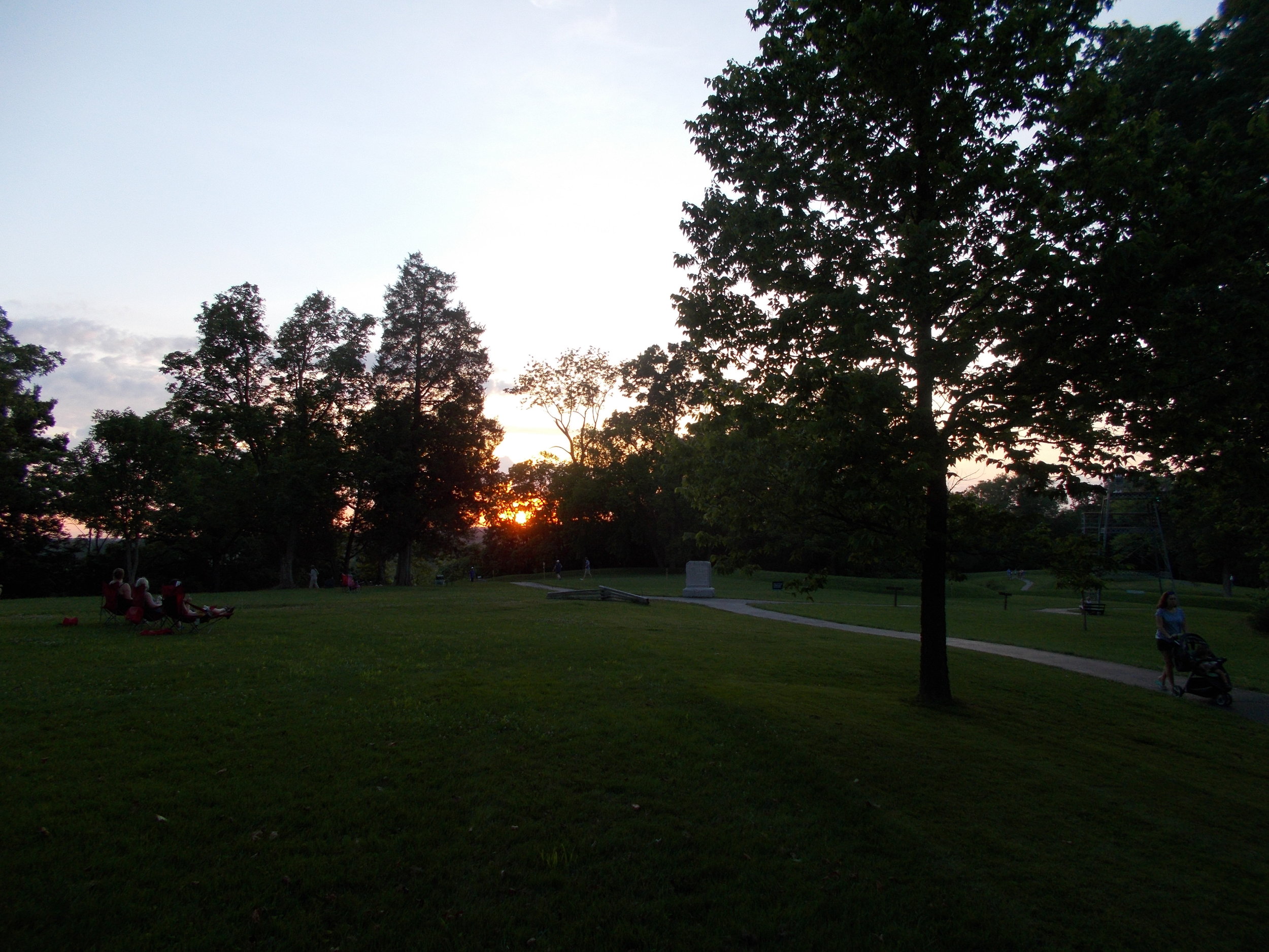 image: sunset at Great Serpent Mound, 06/17/2017; photo looking towards coiled tail and setting sun beyond -- body of Serpent stretches towards right of photo and curves back towards setting sun.